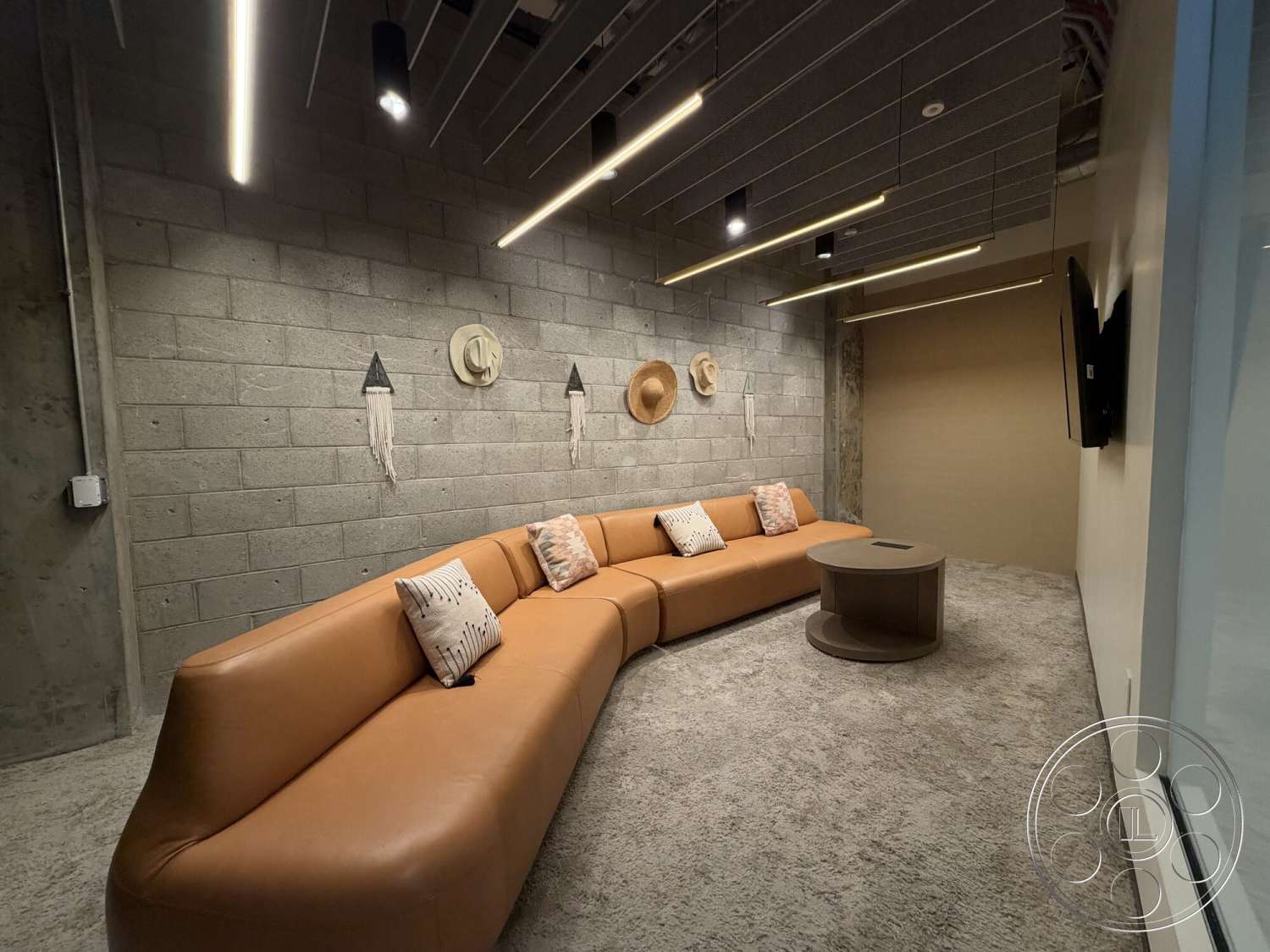 Office 130 - concrete block walls, minimalist coffee table, exposed concrete ceiling, textured carpet flooring, recessed LED lighting, leather curved sofa