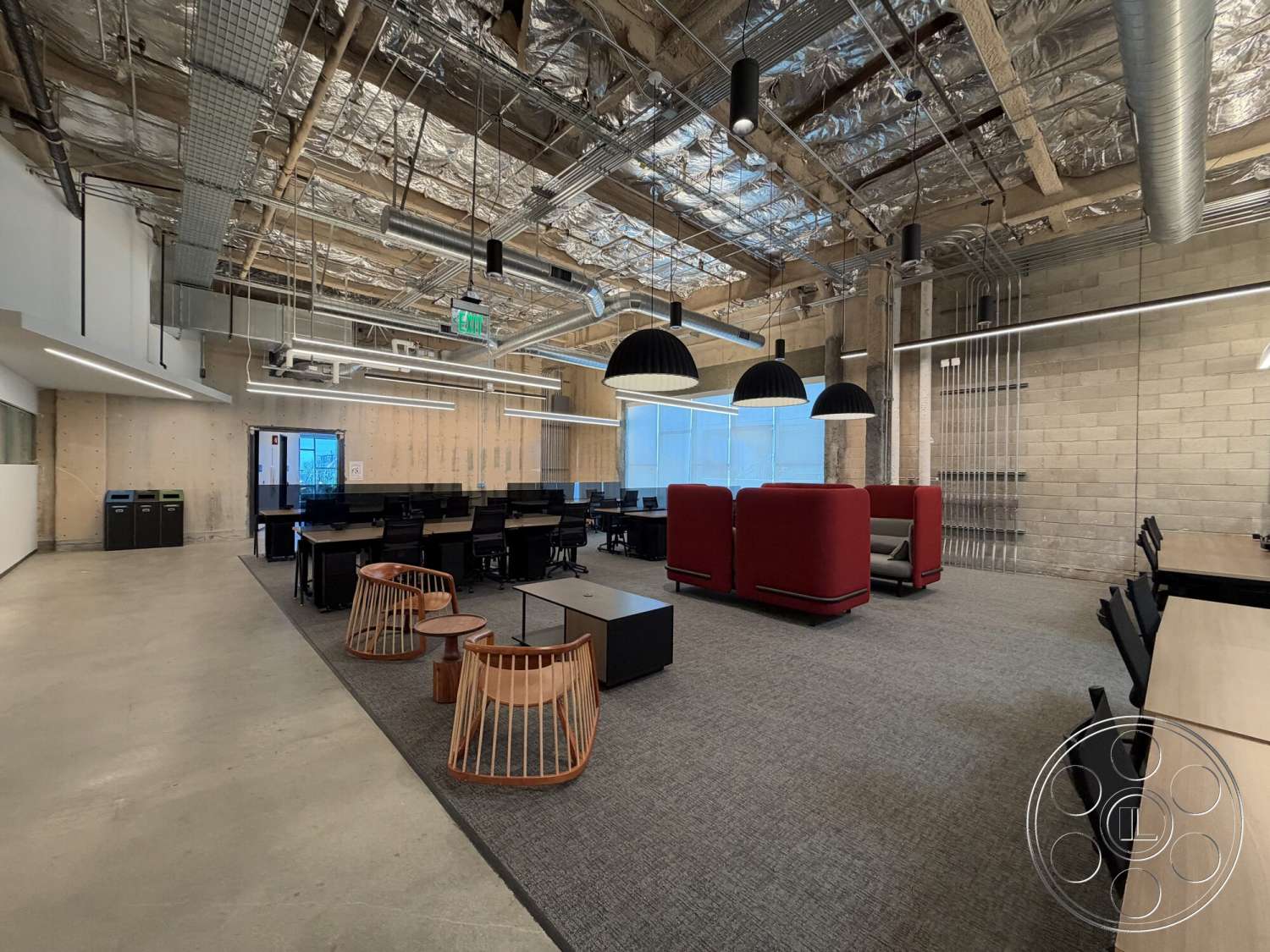 Office 130 - concrete floor, industrial lighting fixtures, textured plaster walls, black office chairs, open office layout, exposed wood ceiling beams, glass office partitions, steel ductwork, red lounge seating areas, modular desks