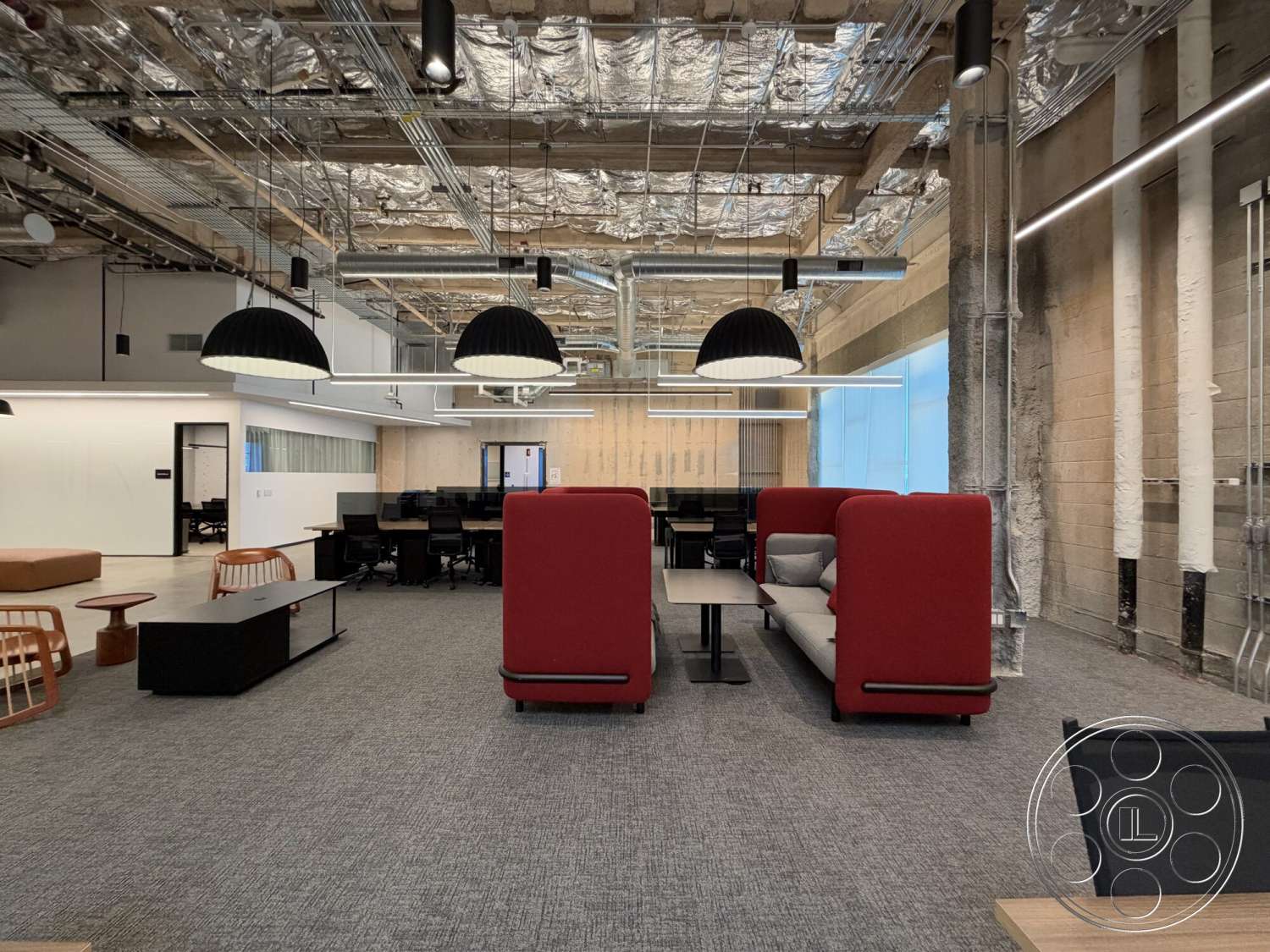 Office 130 - concrete walls, black pendant lighting, open office layout, task chairs, glass partition walls, steel support columns, modern office design, carpet office flooring, wooden conference table, exposed metallic ceiling panels, red upholstered seating booths
