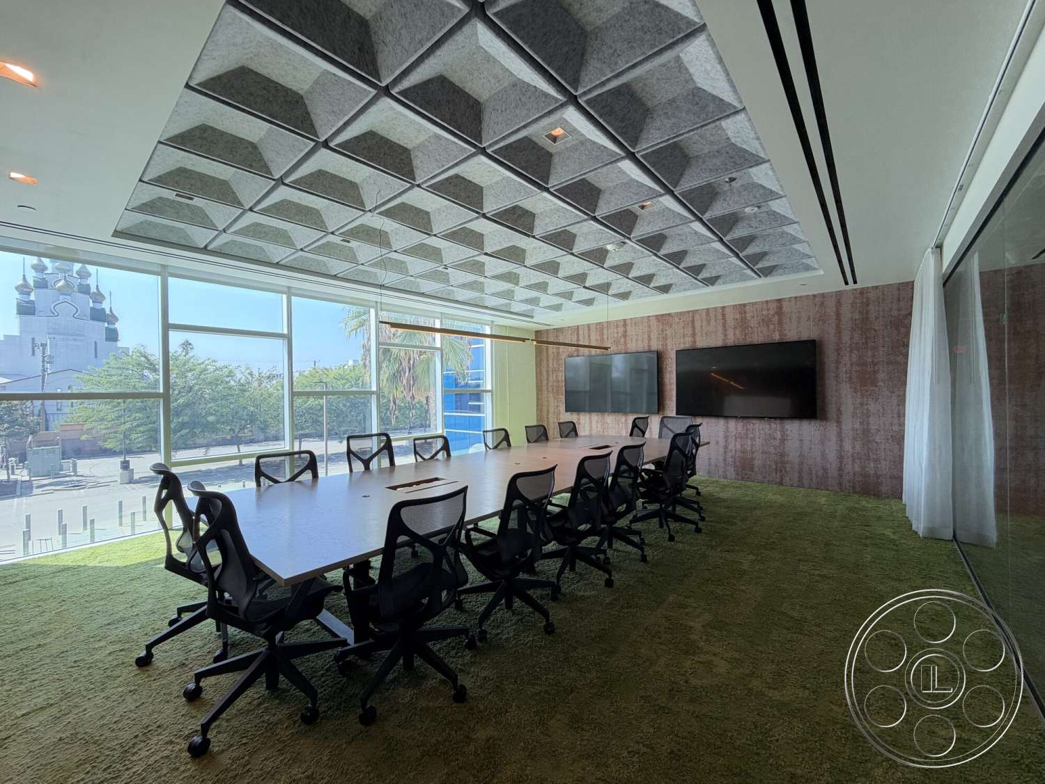 Office 130 - acoustic ceiling tiles, rectangular conference table, glass wall panels, ceiling-mounted lighting fixtures, large panoramic windows, textured fabric wall treatment, green carpet flooring, black rolling office chairs, dual wall-mounted televisions, urban view setting