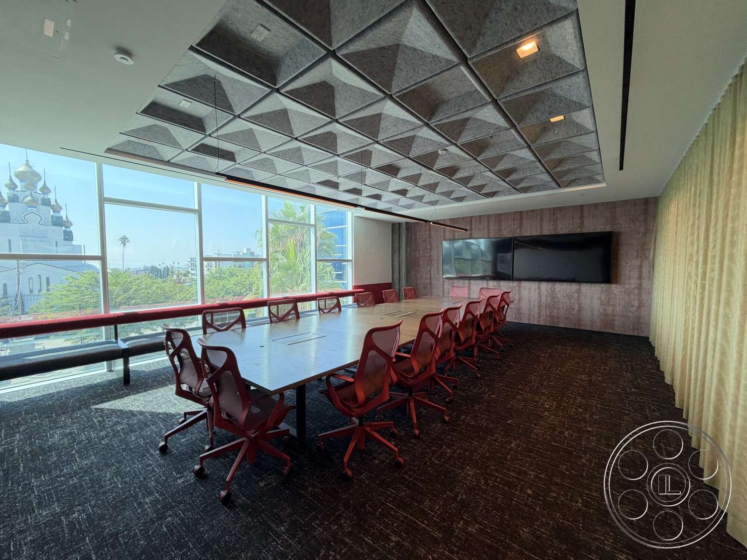 Office 130 - wall-mounted television, large floor-to-ceiling windows, interior conference room, textured ceiling tiles, dark carpet flooring, wood conference table, fabric seating chairs, dimensional wall panels, decorative window drapery