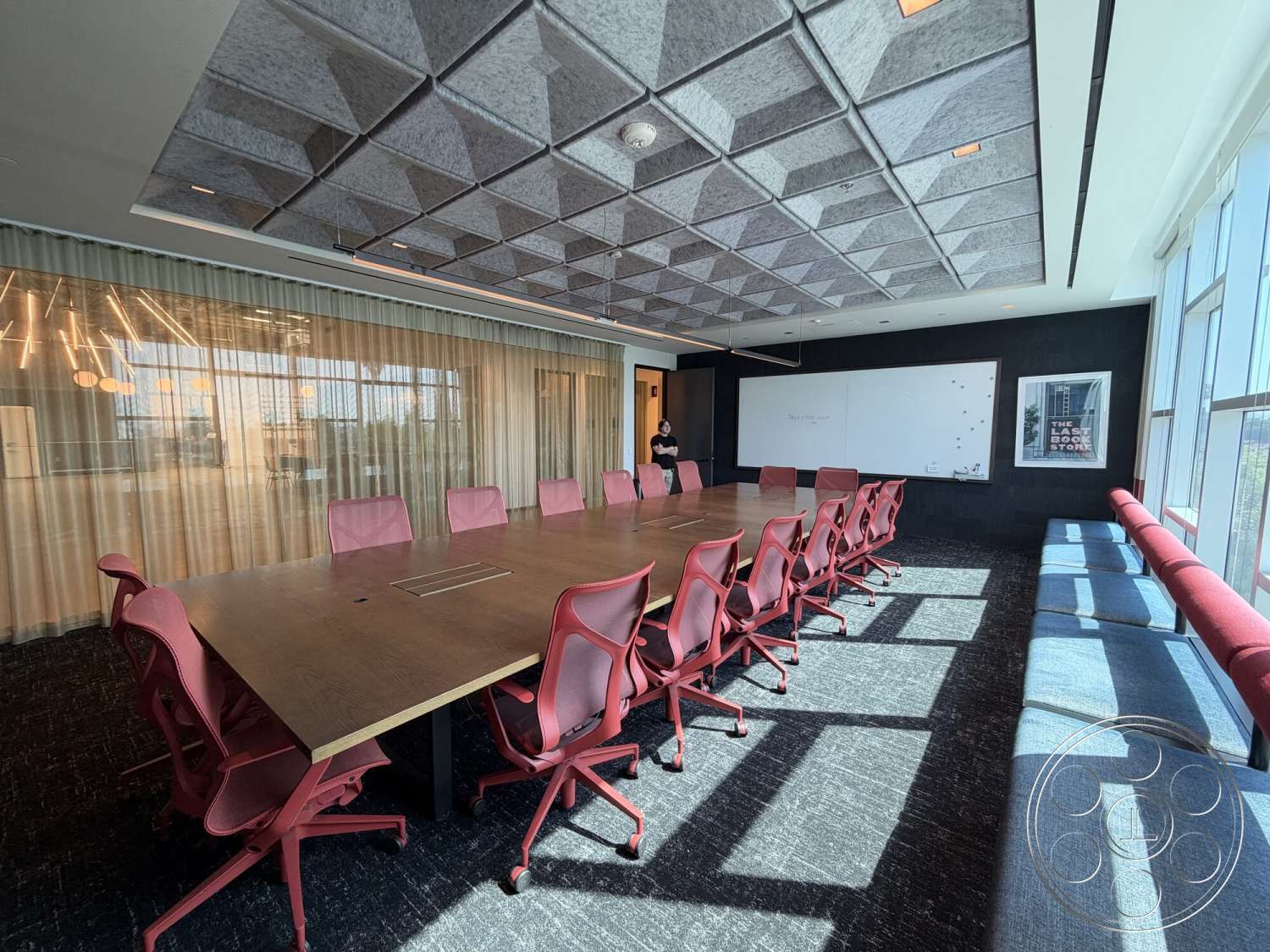 Office 130 - floor-to-ceiling windows, carpet flooring, textured wall detail, acoustic ceiling tiles, glass partition walls, interior conference room, wood conference table, red office chairs, floating light fixtures, dark panel wall