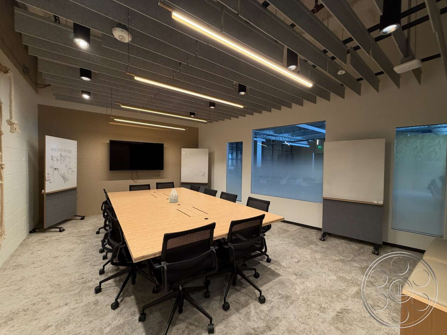 Office 130 - wall-mounted television, concrete flooring, textured wall finish, ergonomic office chairs, glass partition walls, acoustic ceiling panels, modern office design, rectangular conference table, whiteboard wall, LED pendant lighting, live edge wood table top