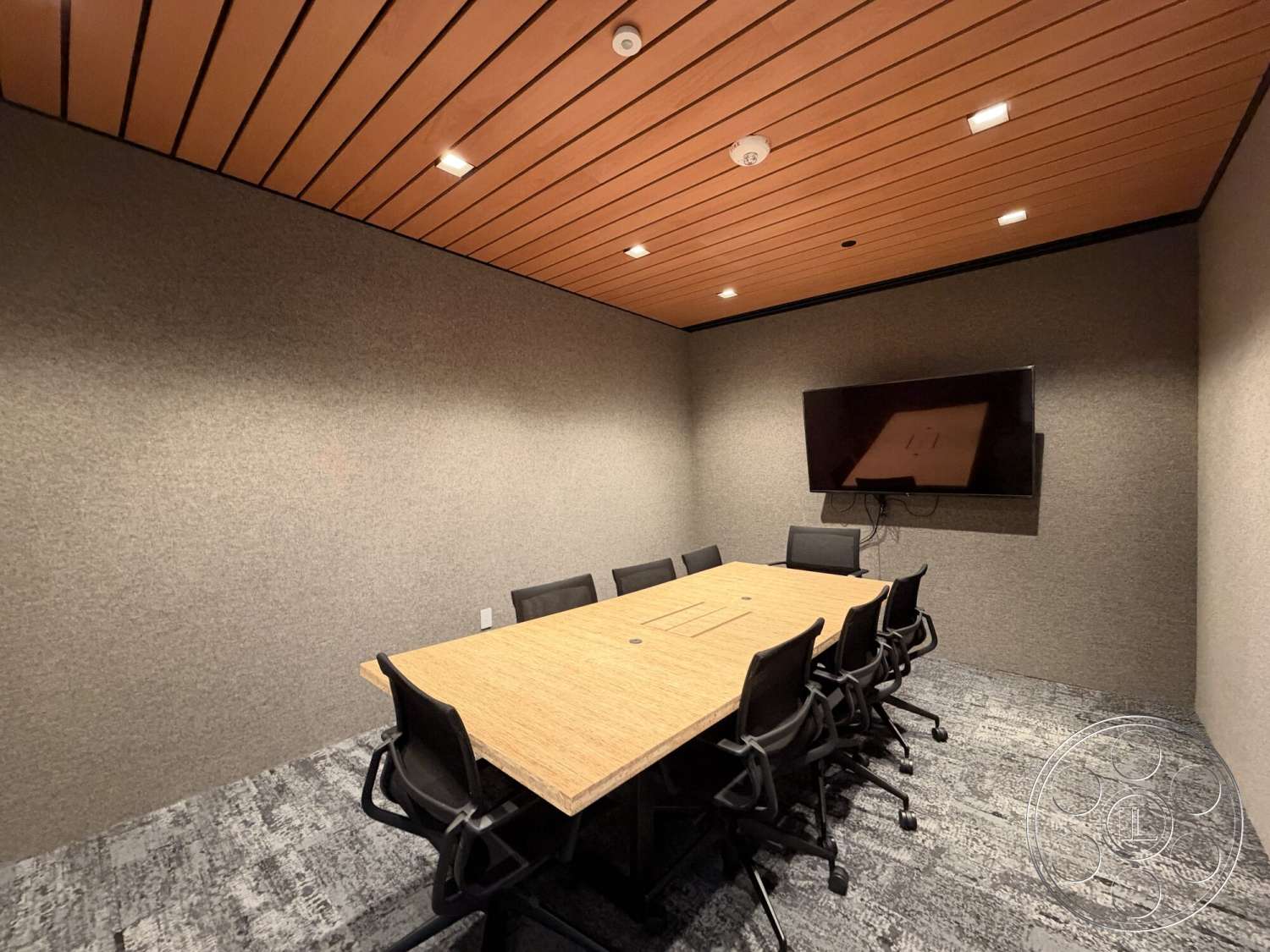 Office 130 - carpeted flooring, fabric wall treatment, black office chairs, flat screen television, conference table, wood slat ceiling