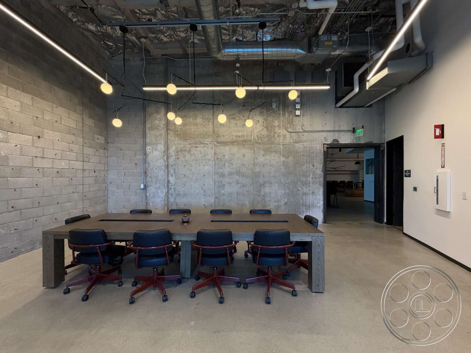 Office 130 - polished concrete flooring, concrete block walls, exposed ceiling structure, open office layout, natural light window, industrial style design, suspended pendant lighting, wood conference table, leather office chairs