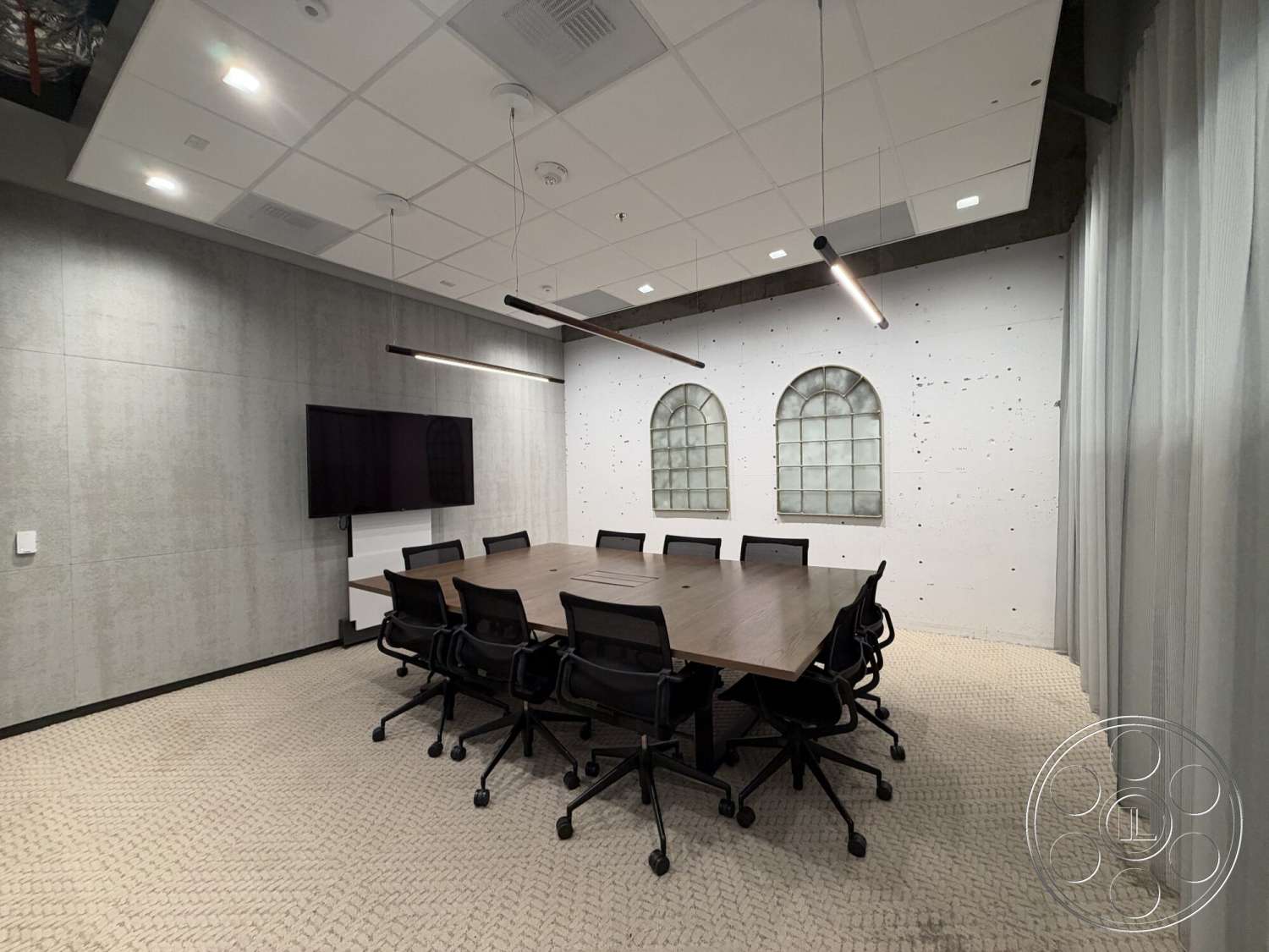 Office 130 - neutral color palette, concrete walls, textured plaster wall, modern office space, suspended ceiling tiles, wood conference table, black ergonomic office chairs, arched window design, herringbone pattern carpet flooring, LED linear pendant lighting, floor-mounted TV display