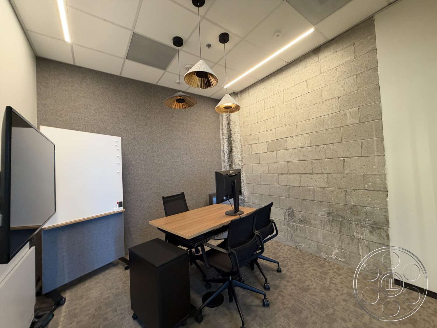 Office 130 - black office chairs, carpet office flooring, LED ceiling lighting, wood conference table, acoustic wall treatment, whiteboard mounted on wall, gray concrete block wall, suspension pendant lights, large flat-screen monitor