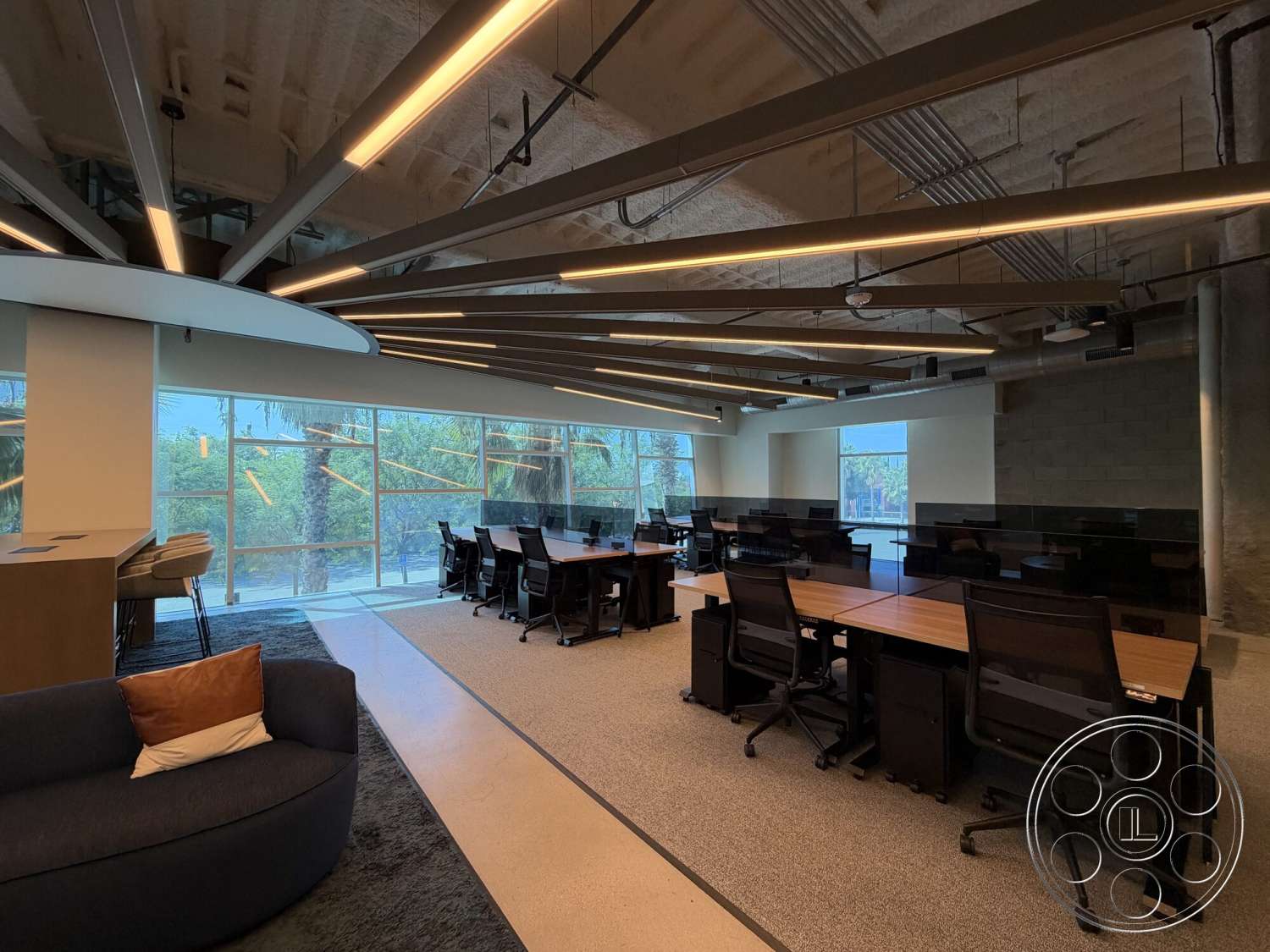 Office 130 - concrete block walls, carpet flooring, industrial lighting fixtures, exposed ceiling beams, textured ceiling finish, glass office partitions, modern office chairs, large windows with outdoor view, hardwood conference table, office interior