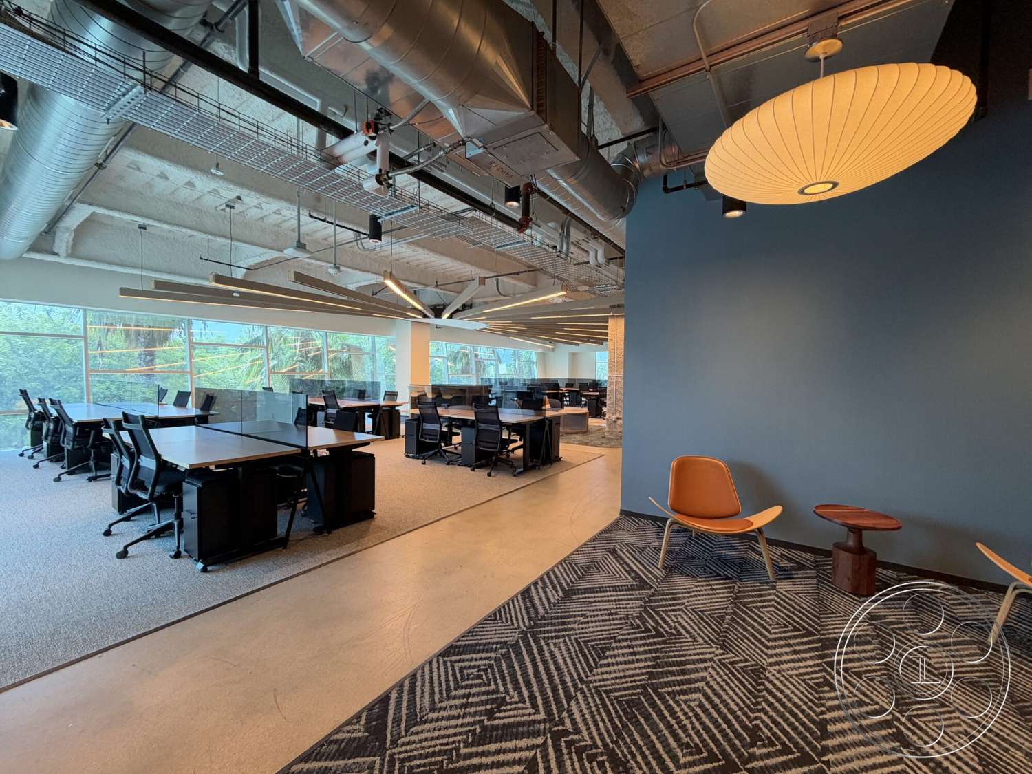 Office 130 - neutral color palette, open layout, concrete flooring, modern design elements, collaborative workspace, textured wall treatment, black office chairs, pendant lighting fixture, interior office space, metal ceiling ductwork, modern office desks, large windows with views, carpeted workspace areas, dark wooden accent furniture, divided work areas, ergonomic seating