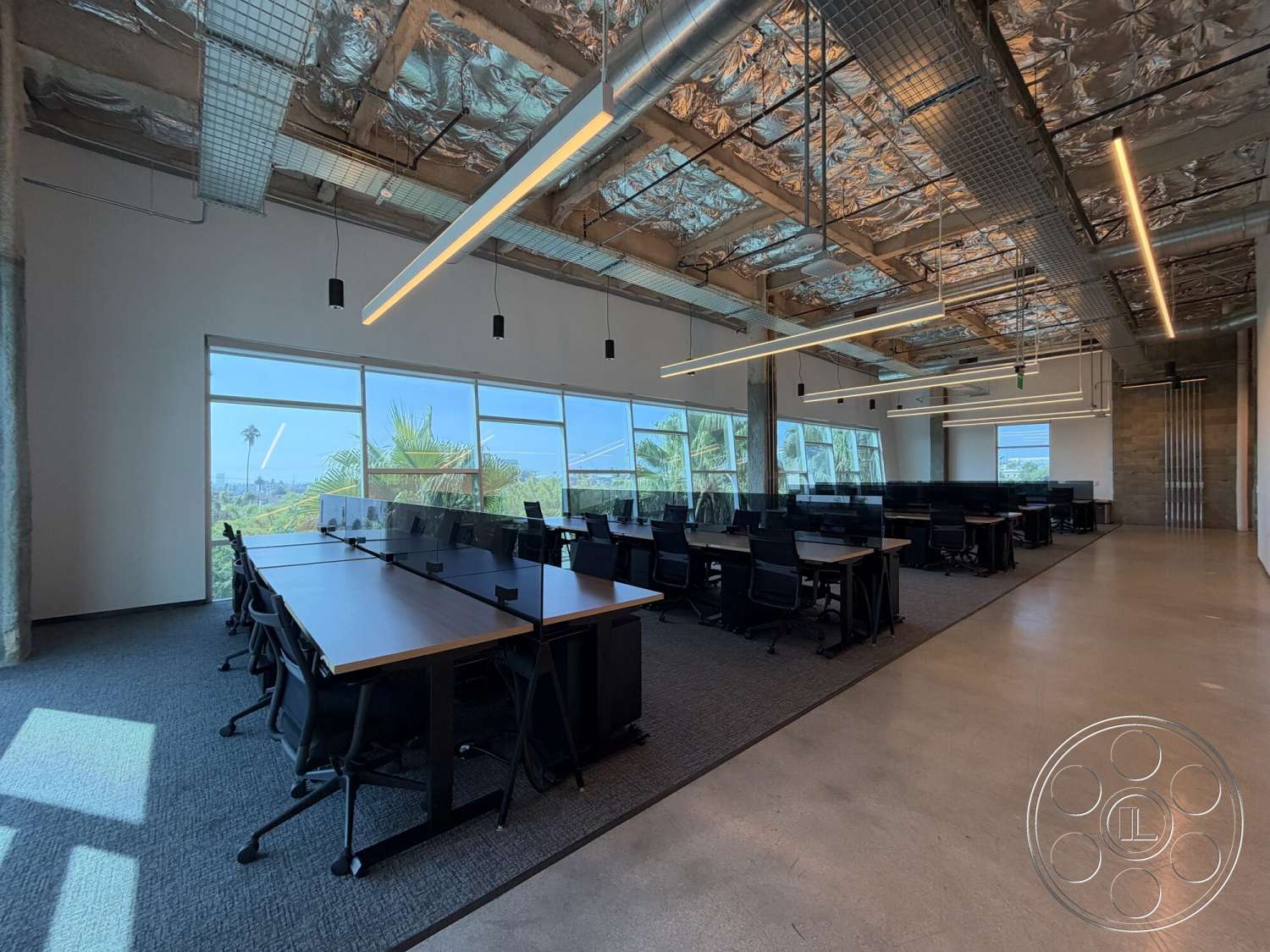 Office 130 - concrete flooring, exposed concrete walls, floor-to-ceiling windows, modern office interior, linear LED ceiling lights, open workspace layout, wooden office desks, black ergonomic office chairs, metal ceiling grid, large glass window view, carpeted office area