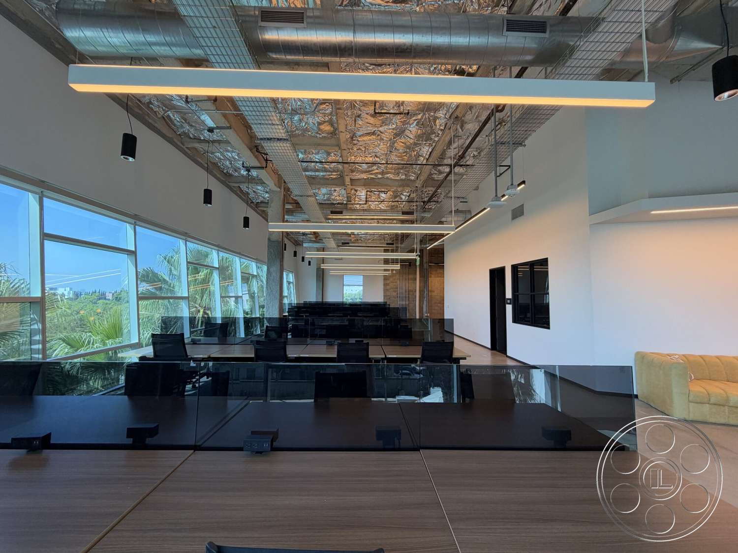 Office 130 - polished concrete flooring, modern aesthetic, large floor-to-ceiling windows, black office chairs, open office layout, neutral painted walls, interior office space, industrial style decor, glass office partitions, collaborative workspace area, exposed ceiling ductwork, wooden conference room table, metal pendant lighting fixtures