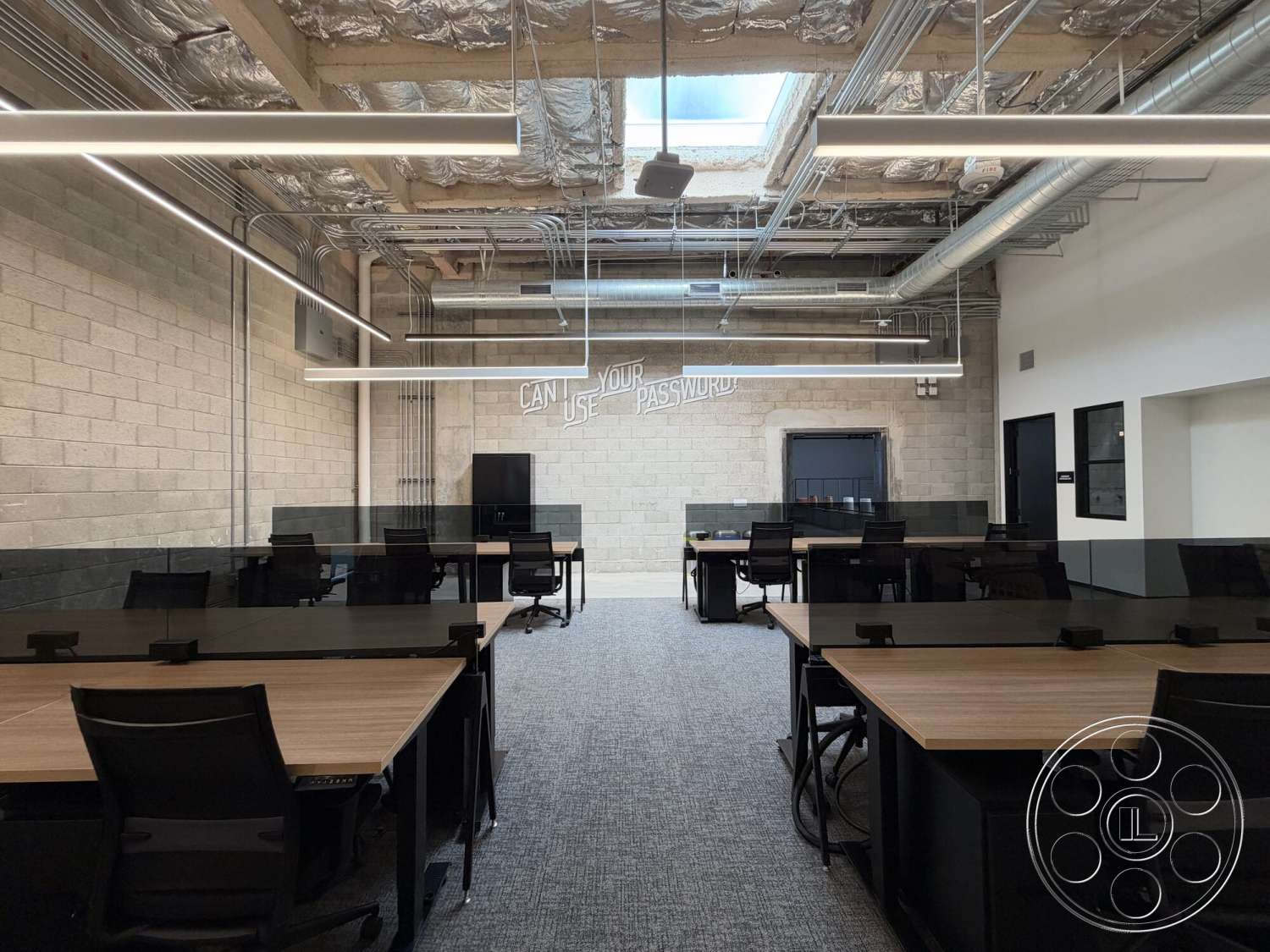 Office 130 - decorative wall art, glass partition walls, carpet office flooring, linear LED ceiling lights, metal ductwork ceiling, exposed concrete block walls, wood conference tables, black rolling office chairs, industrial office space