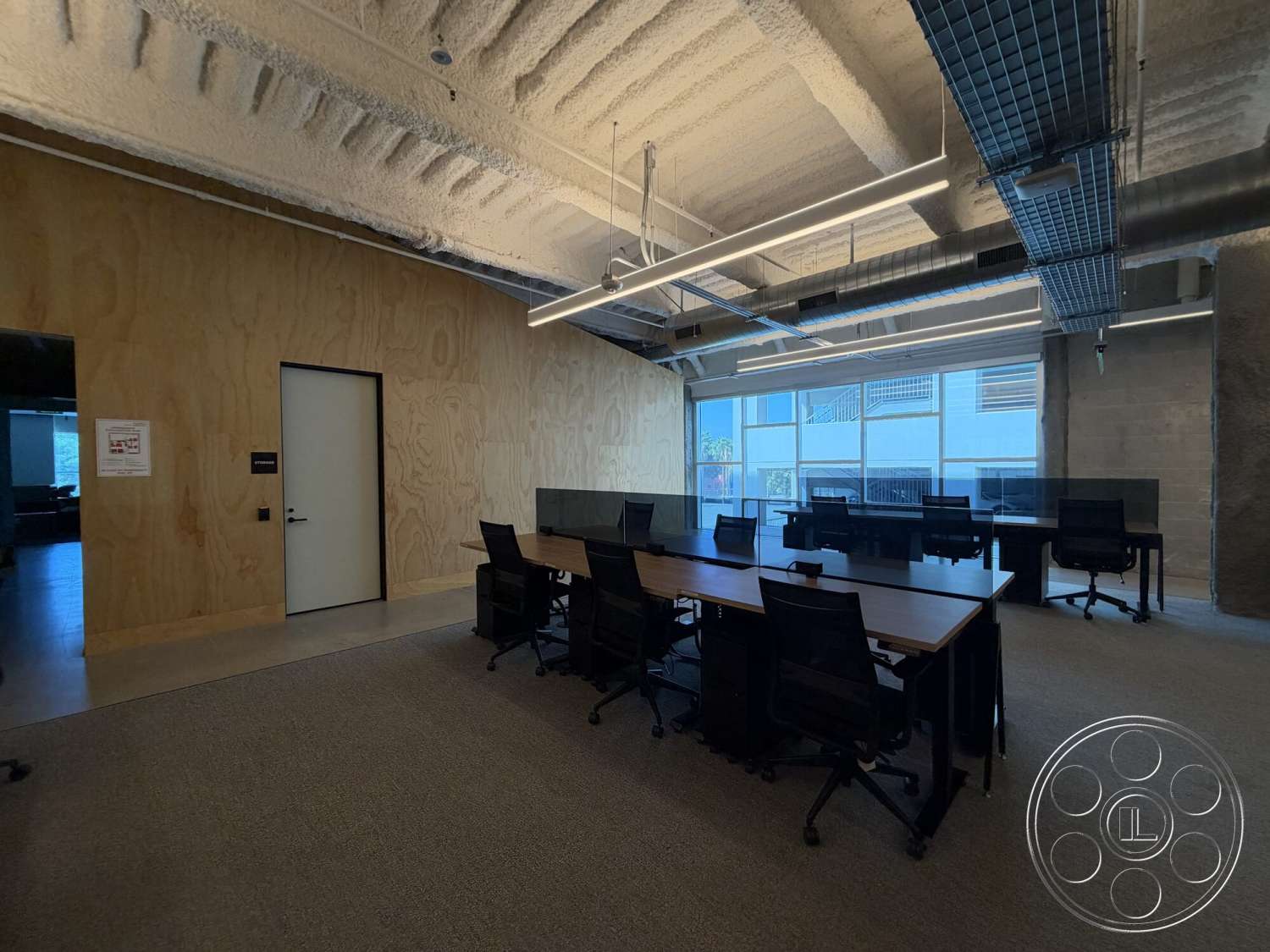 Office 130 - floor-to-ceiling windows, open office layout, interior office space, carpet office flooring, rectangular conference table, industrial-style lighting fixtures, glass office partitions, modern office chairs, exposed concrete ceilings, plywood wall paneling