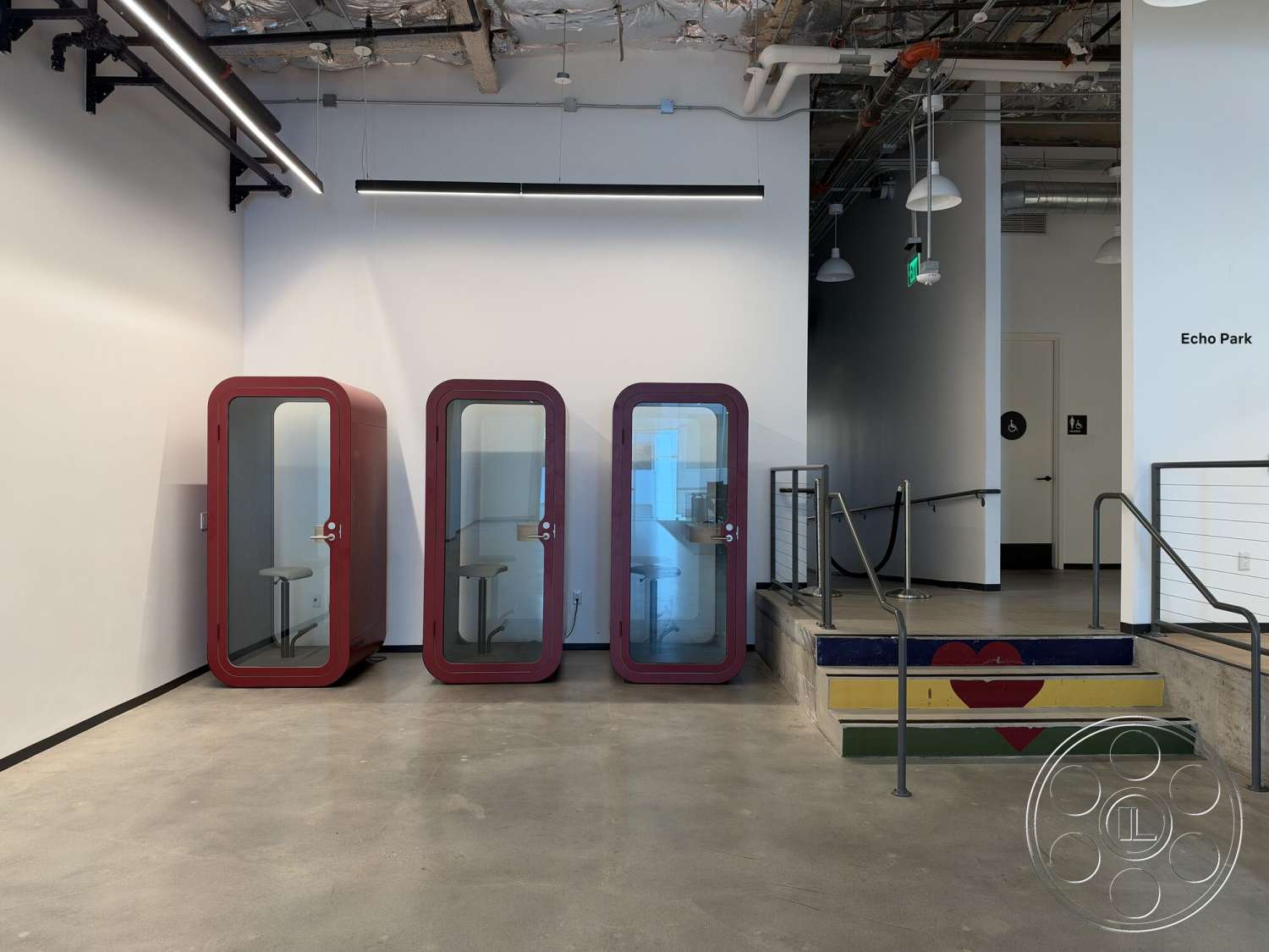 Office 130 - contemporary interior design, white painted walls, exposed concrete flooring, LED strip lighting, industrial style space, open ceiling with exposed ductwork, glass office pods, metal railing with wood accents, colorful painted staircase
