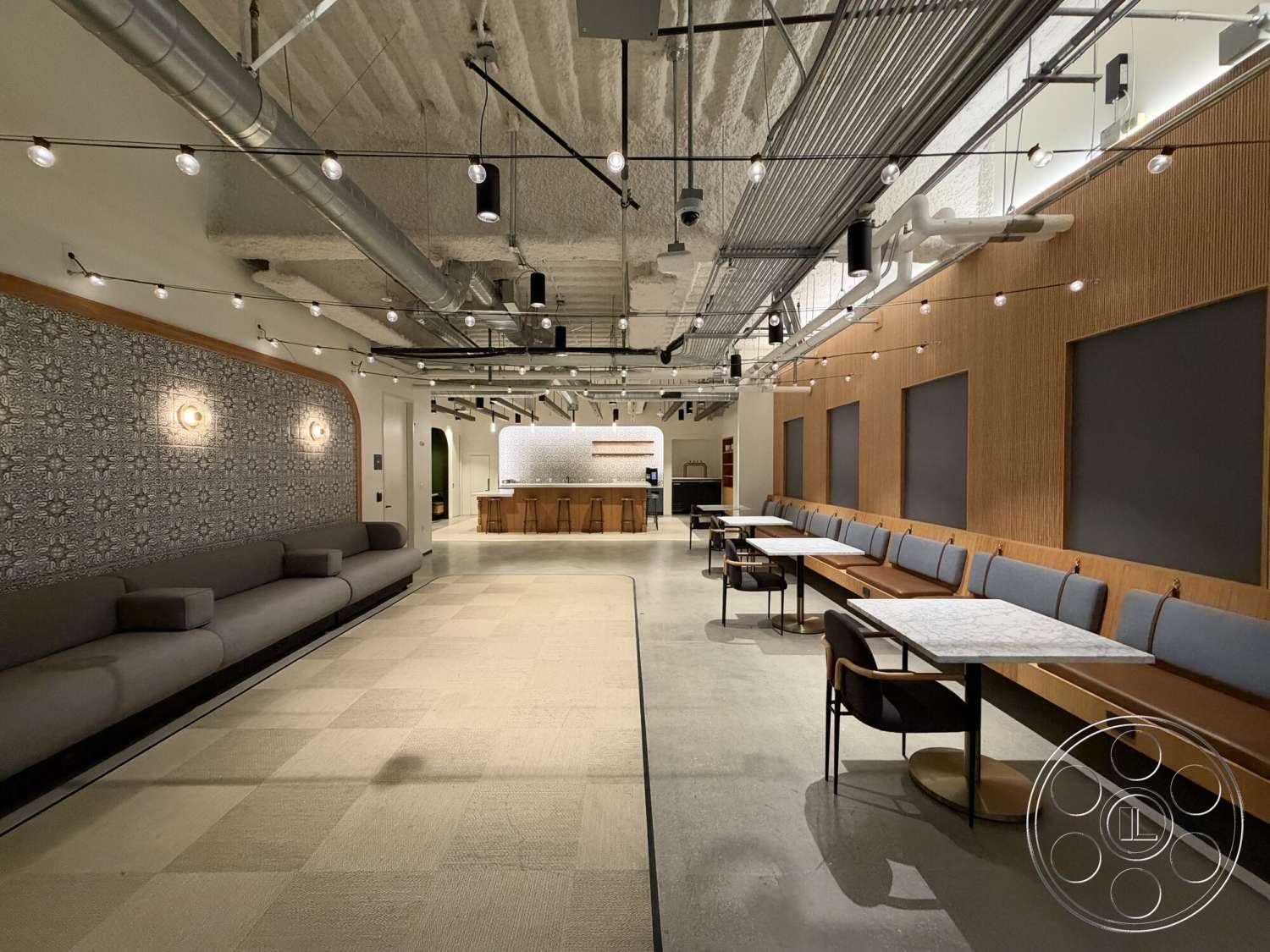 Office 130 - concrete flooring, metal bar stools, textured plaster ceiling, open layout design, wood panel accent wall, upholstered seating area, wall-mounted lighting fixtures, marble tabletop surfaces, geometric patterned wall treatment