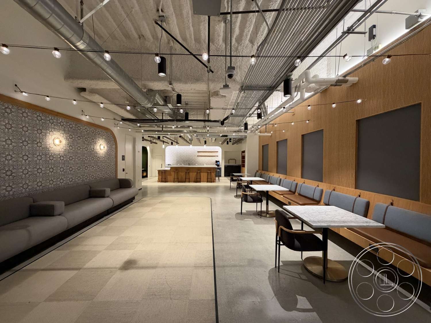 Office 130 - polished concrete flooring, ambient lighting, casual dining space, exposed ductwork, wood accent wall, metal light fixtures, modern seating area, open layout design, textured ceiling panels, functional kitchen area, soft upholstered seating, ornate tile feature wall, custom wood bench seating, marble dining tables, high-top bar stools