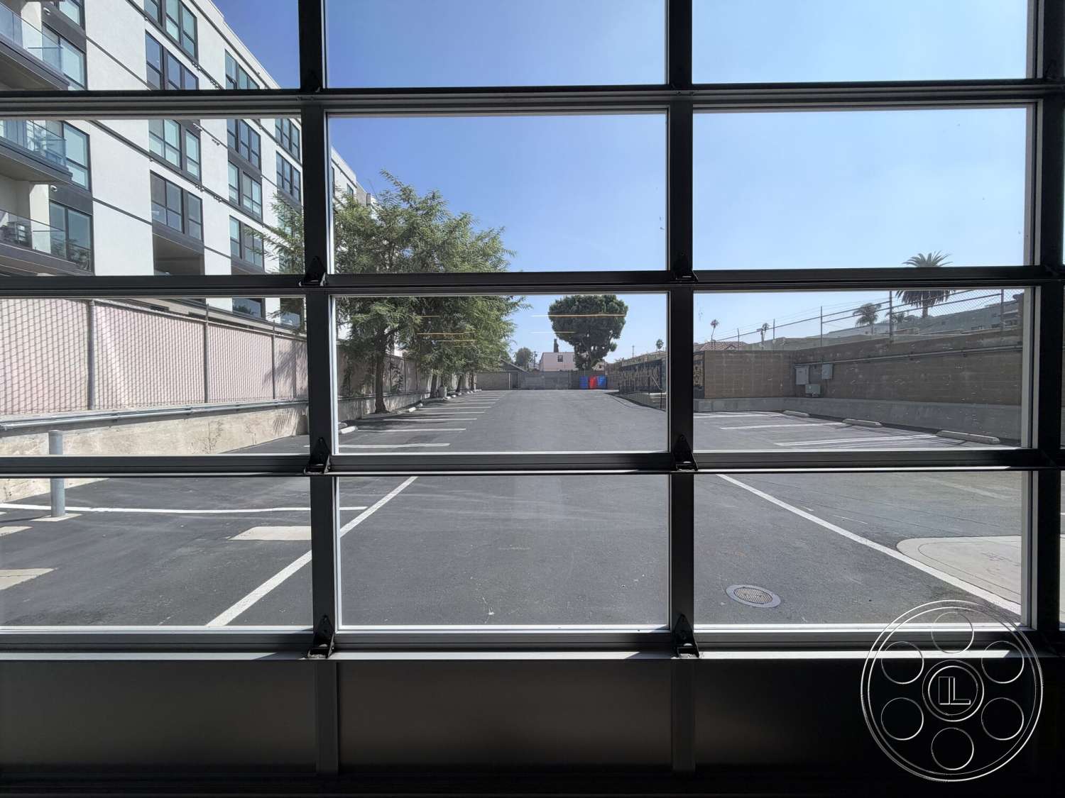 Office 130 - exterior, paved driveway, brick wall, metal fence, urban environment, glass garage door, landscaped trees, concrete parking lot, linear parking layout, modern apartment building
