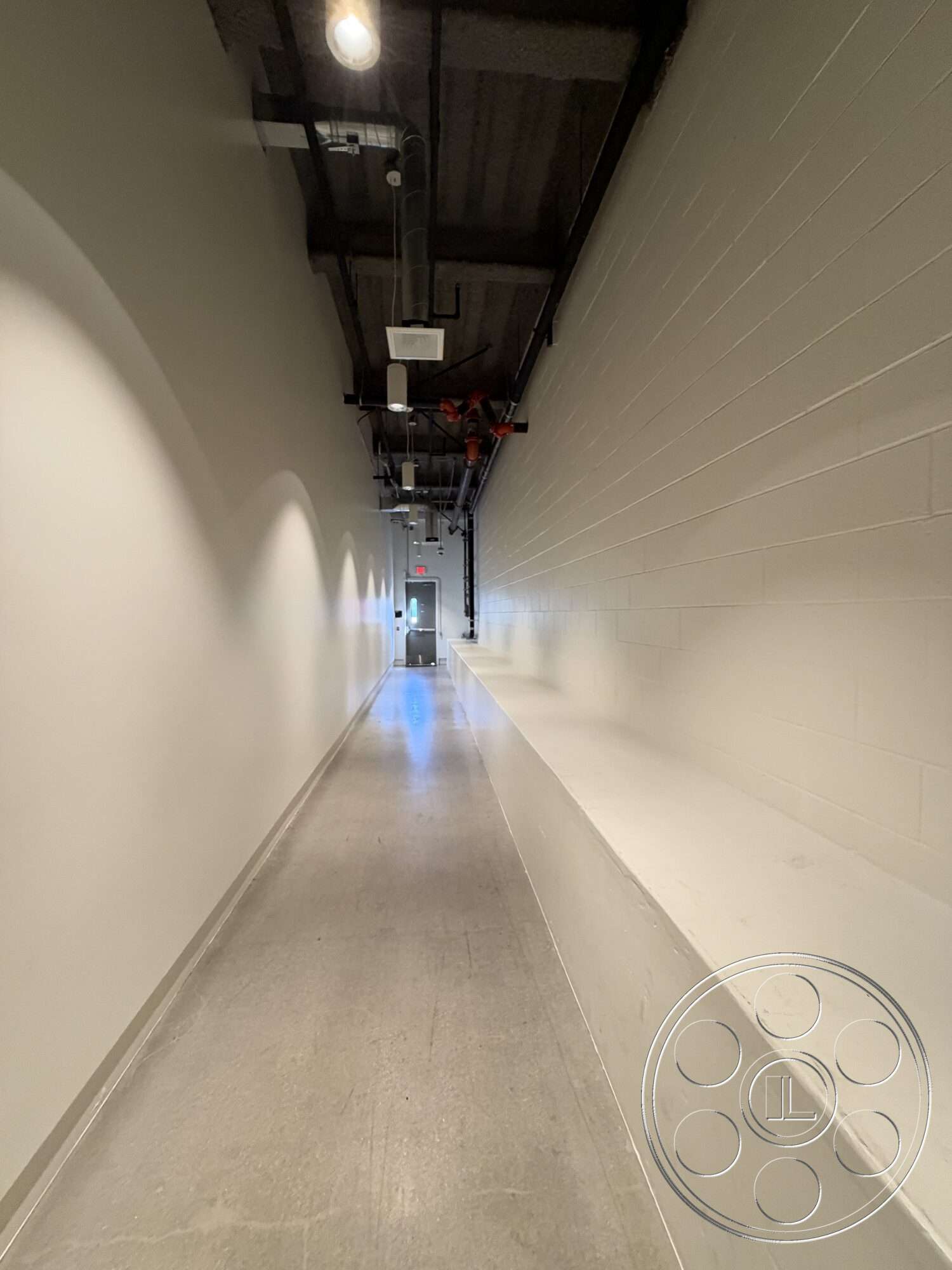 Office 130 - concrete floor, industrial lighting, linear layout, white painted walls, interior corridor, exposed ceiling design, fire suppression piping, large exit door