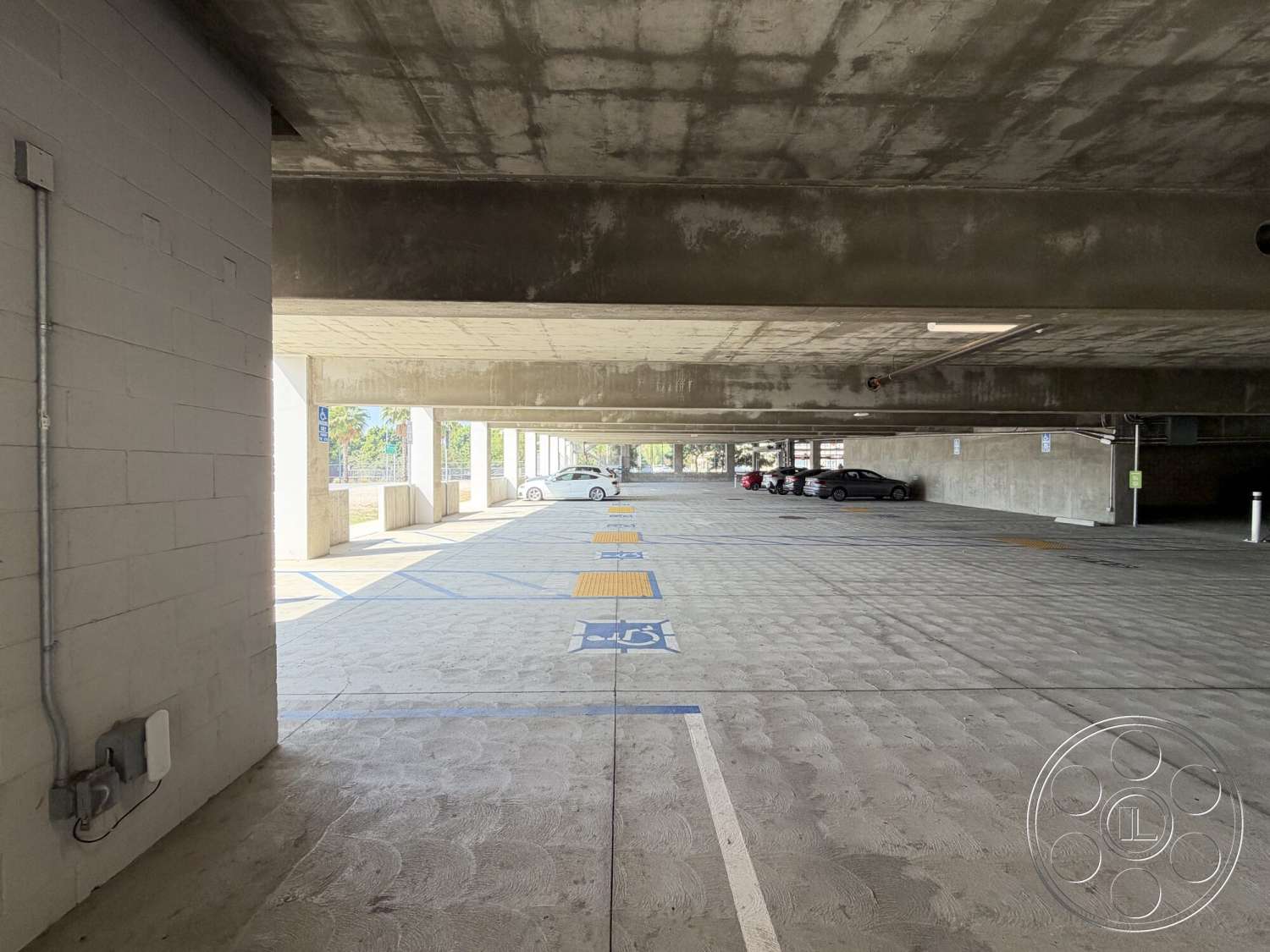 Office 130 - open layout, concrete floor, modern design elements, concrete walls, urban environment, concrete structure, concrete ceiling, exterior parking garage, linear strip lighting, parking spaces with painted lines, accessibility parking spaces, partial natural light exposure