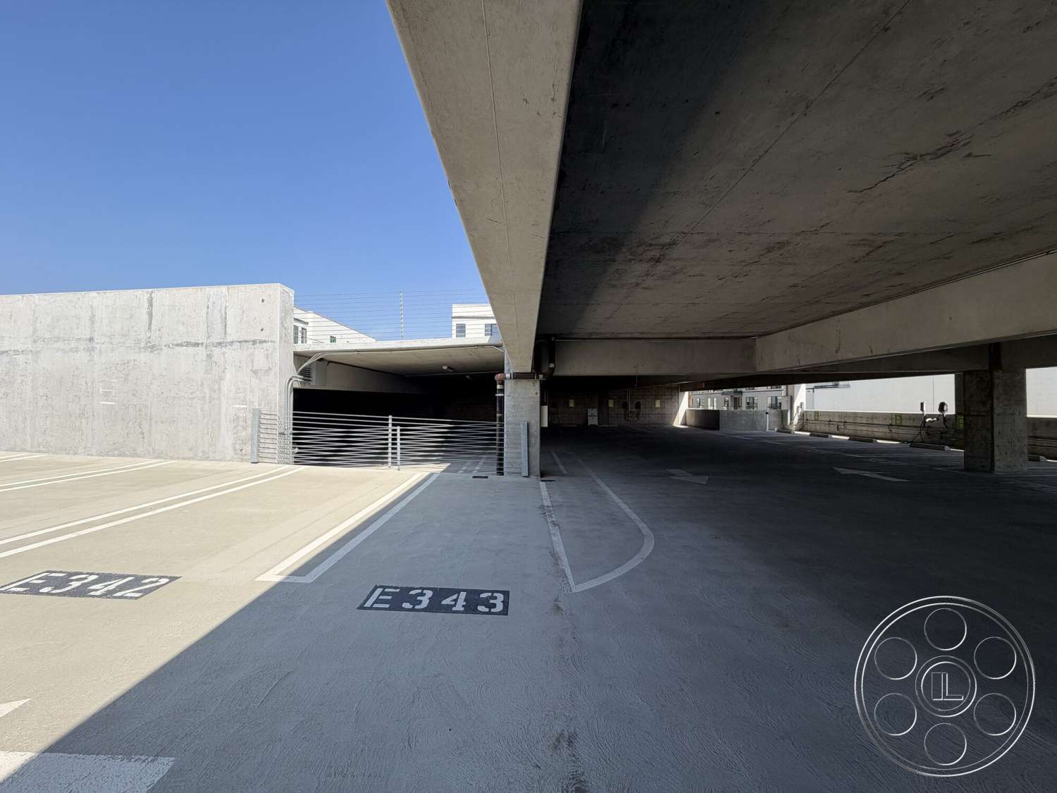 Office 130 - concrete walls, outdoor setting, urban architecture, concrete parking floor, metal railing details, concrete ceiling beams, open parking layout, striped parking lines, exposed concrete parking structure, functional parking design