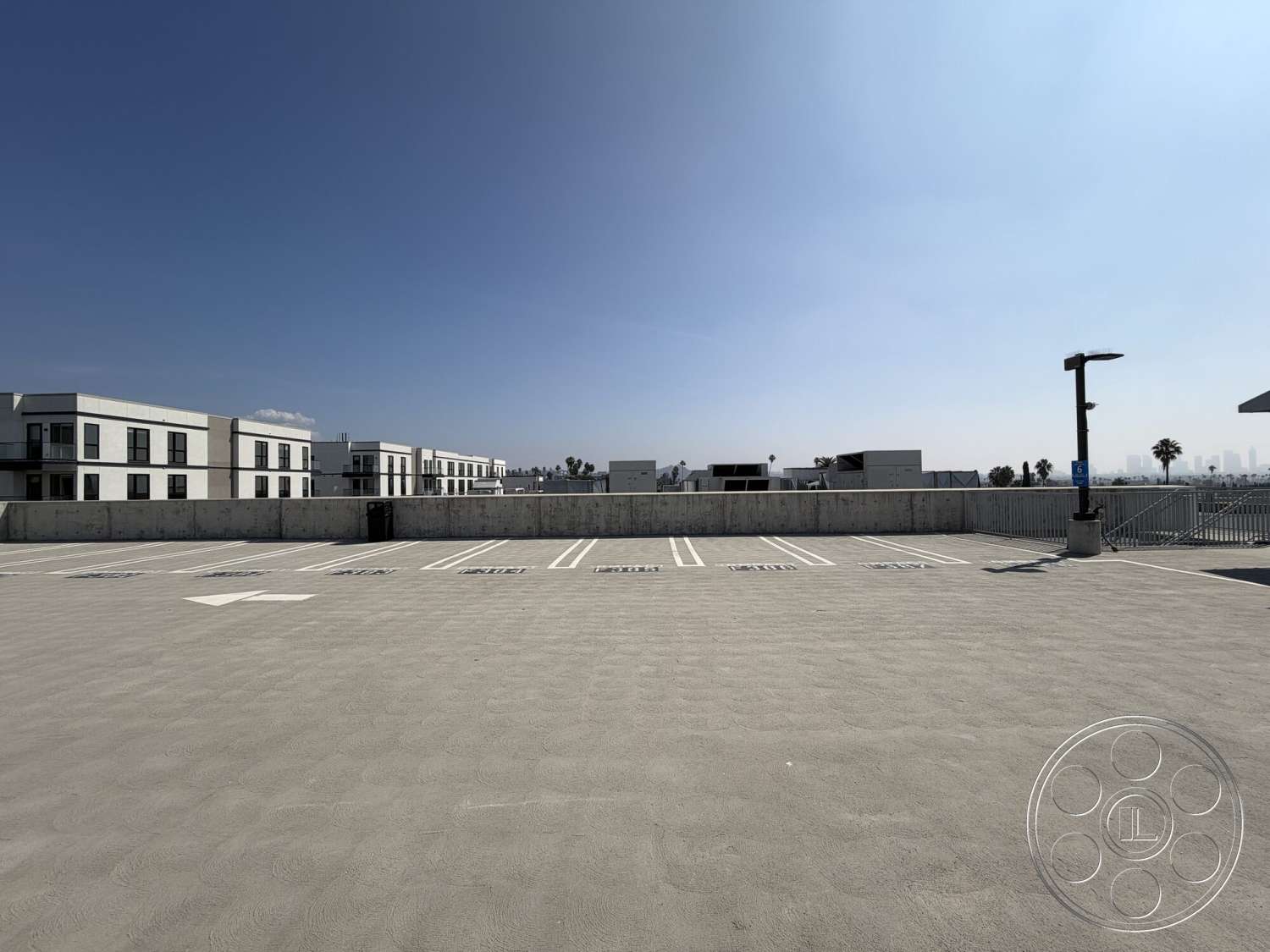 Office 130 - clear blue sky, concrete parking surface, flat rooftop design, exterior parking lot, open urban setting, surrounding modern residential buildings