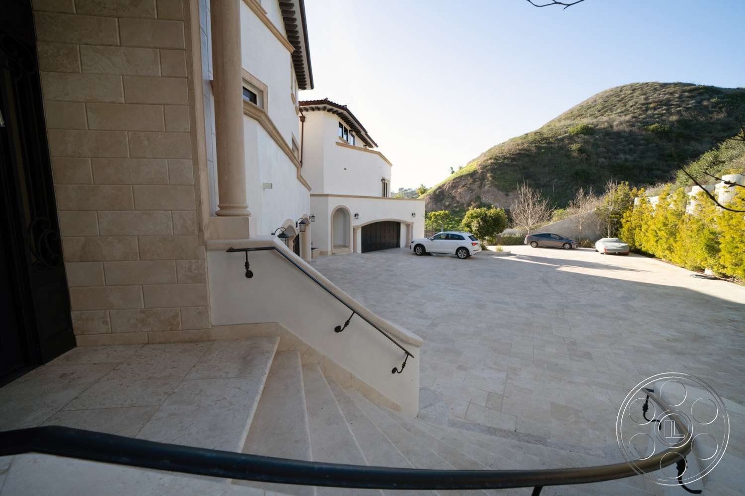 Medit 169 - exterior, landscaped garden, circular driveway, mountain view, arched doorway, decorative column details, smooth stucco walls, stone staircase, travertine stone driveway, valley hillside setting