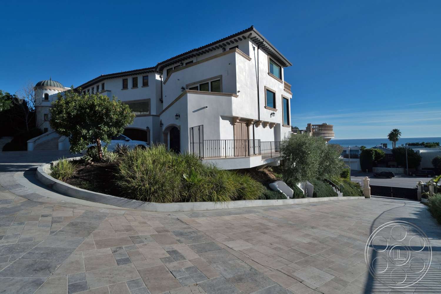 Medit 169 - exterior, landscaped garden, ocean view, sloped driveway, terracotta roof tiles, arched doorways, coastal setting, balcony with wrought iron railing, flat roof design, multi-level home, stucco house facade, concrete stairway, pavers driveway, ground cover plants