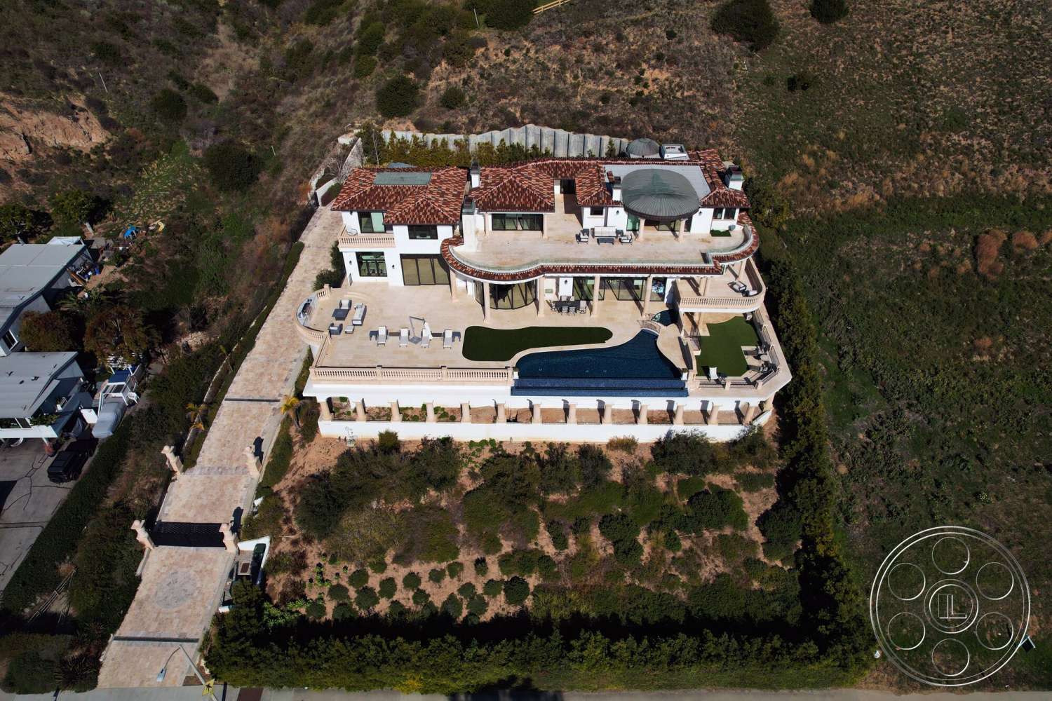Medit 169 - exterior, paved driveway, glass sliding doors, outdoor seating area, concrete patio, vaulted ceiling, city skyline view, terracotta roof tiles, stucco walls, hillside location, wooden outdoor furniture, landscape garden, stone pool deck, rectangular infinity pool, Mediterranean style villa, brick perimeter wall