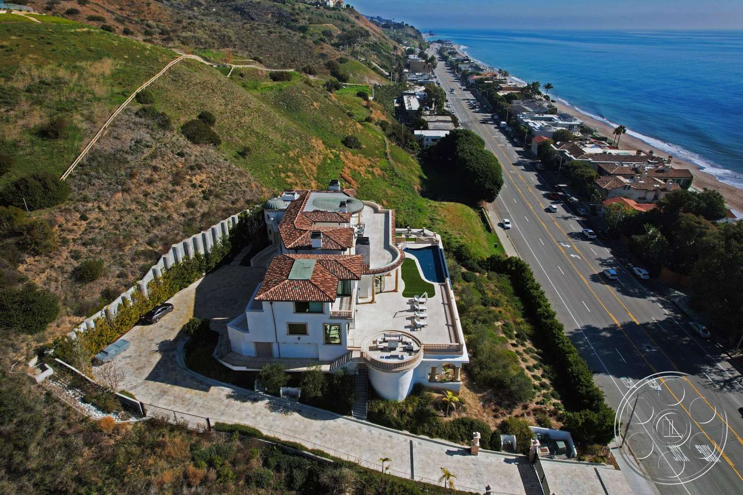 Medit 169 - exterior, landscaped garden, floor-to-ceiling windows, vaulted ceiling, outdoor lounge area, concrete driveway, stucco walls, terracotta tile roof, infinity pool, coastal view, hillside location, modern residential architecture, concrete retaining wall, stone patio flooring, curved balcony railing, wraparound balcony, raised terrace, semi-circular design elements