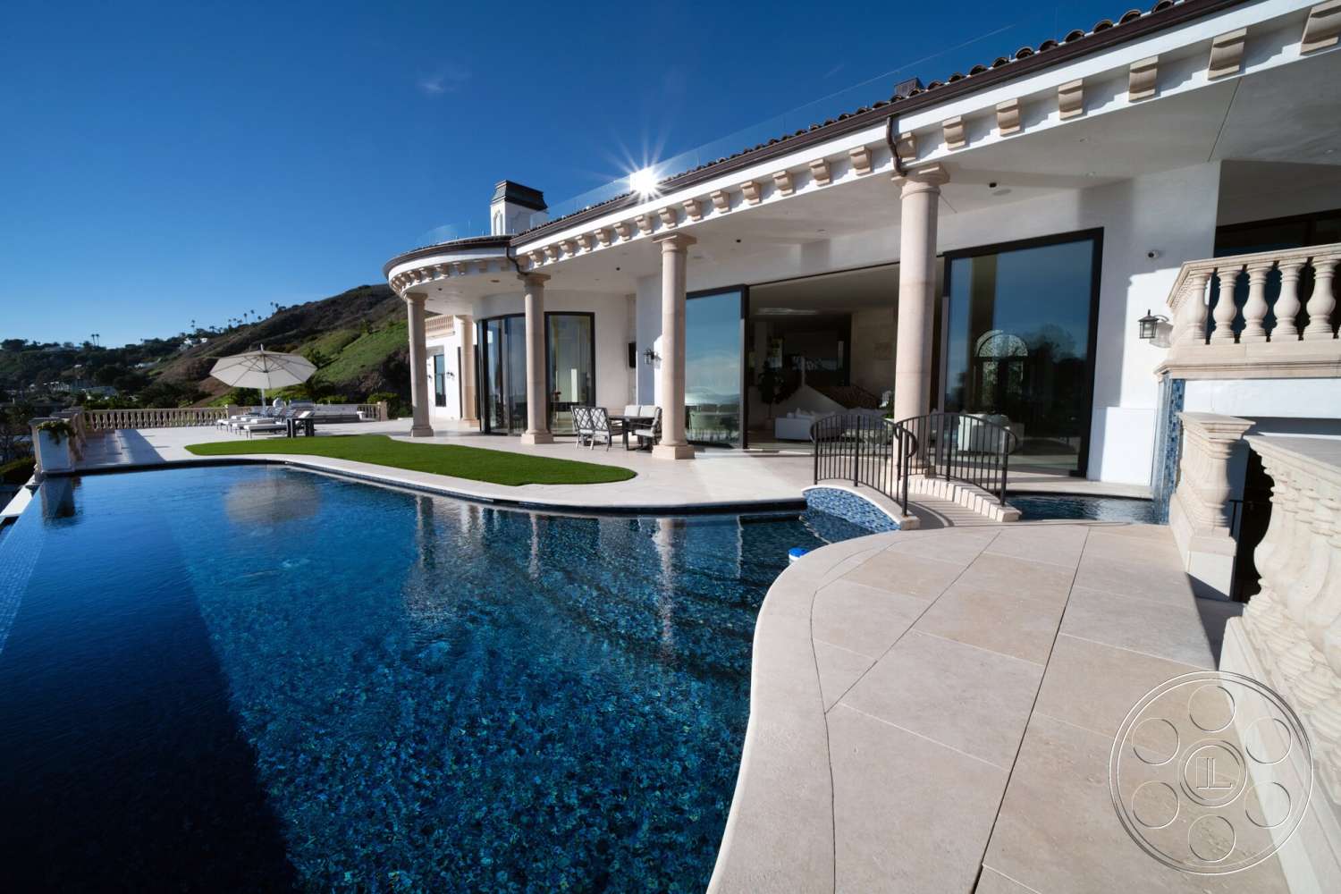 Medit 169 - exterior, glass sliding doors, outdoor dining area, modern architectural style, infinity pool, white stucco exterior, tiled pool deck, stone columns, stone wall features, landscaped garden area, arched balcony railing, sunny hillside location, concrete patio surface, open patio layout