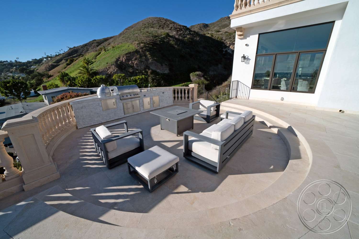 Medit 169 - exterior, glass sliding doors, modern architectural style, stone patio flooring, aluminum outdoor furniture, landscaped hillside view, stainless steel outdoor kitchen, circular patio, concrete railing, sandy beige stone walls