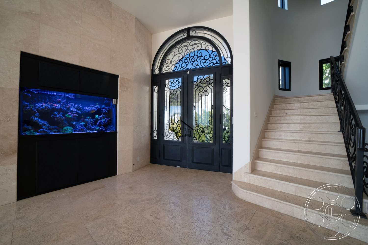 Medit 169 - high ceilings, curved staircase, black wrought iron railing, smooth plaster walls, travertine flooring, ornate entry door, large aquarium feature, multi-paneled windows, decorative door arch