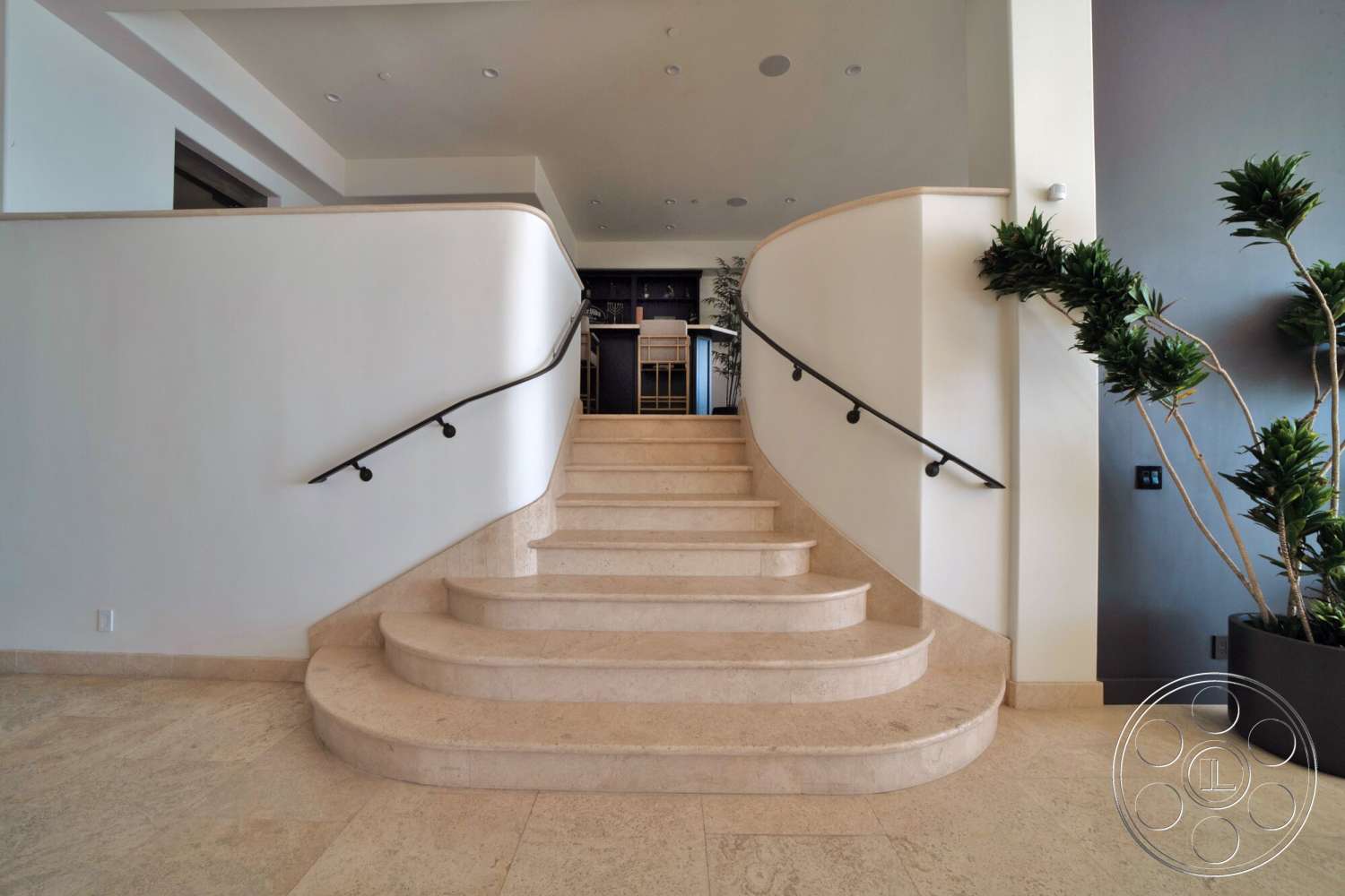 Medit 169 - open concept layout, light-colored flooring, smooth white walls, curved staircase, minimalist architectural style, potted ornamental plants, black metal handrail, travertine staircase steps, integrated wall lighting