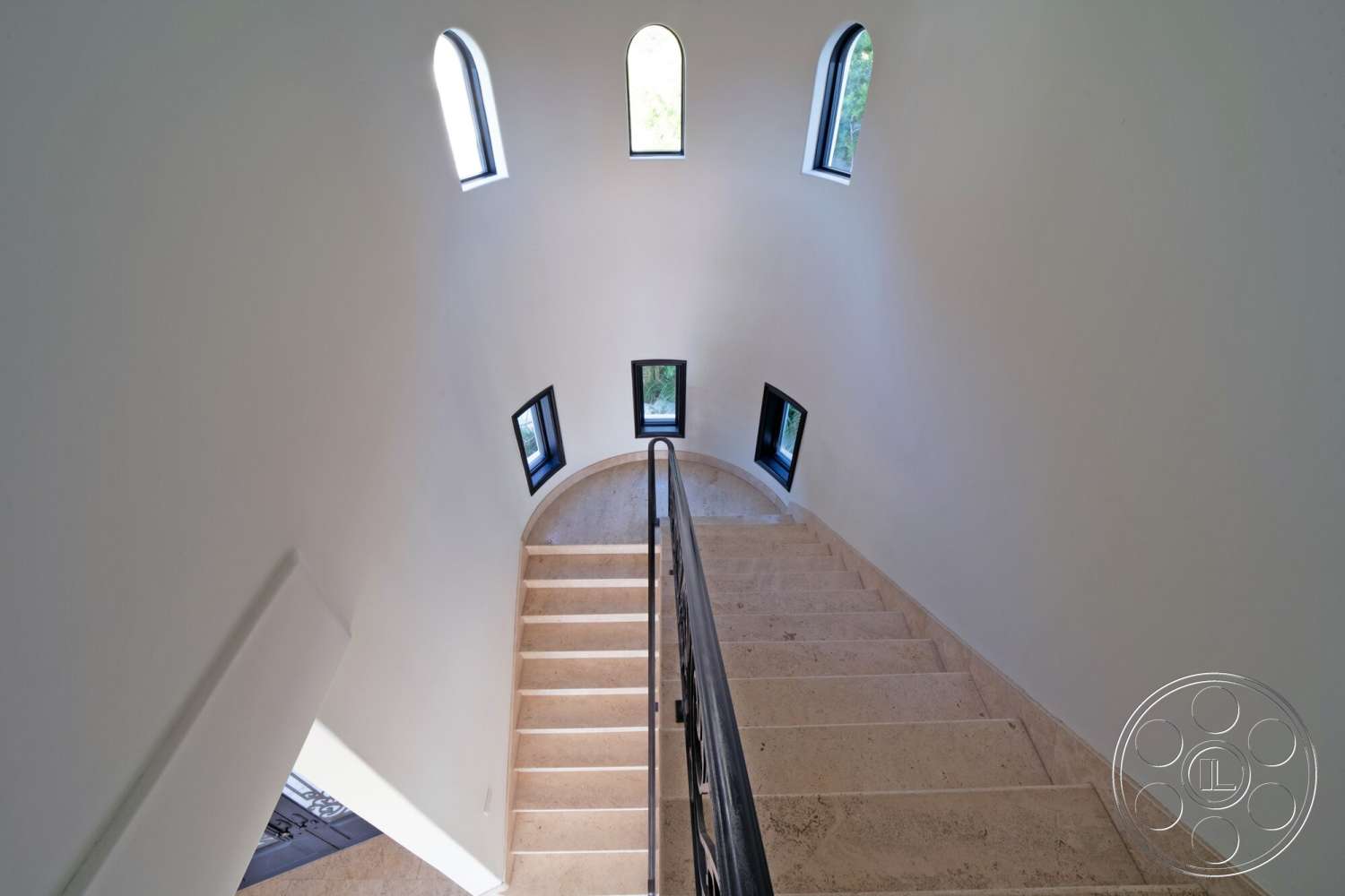 Medit 169 - open space, spiral staircase, modern architectural style, black metal railing, natural light from windows, curved wall design, arched windows, white plaster walls, minimalistic interior, stone staircase steps