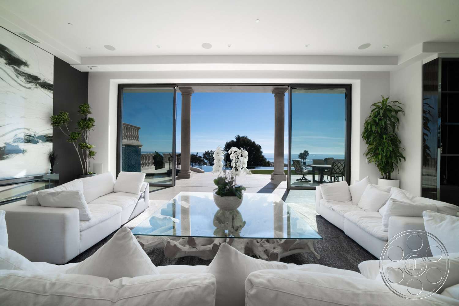 Medit 169 - natural light, contemporary style, minimalist design, glass coffee table, glass sliding doors, floor-to-ceiling windows, vaulted ceiling, marble flooring, decorative potted plants, black accent wall, white upholstered sectional sofa, oceanview setting