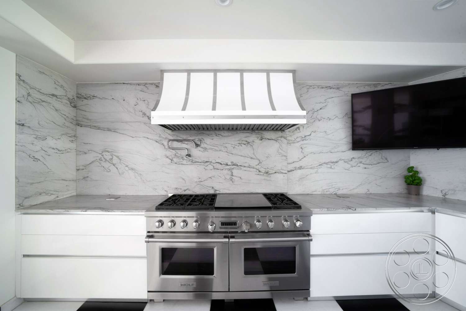 Medit 169 - marble backsplash, modern kitchen design, stainless steel range hood, white lacquered kitchen cabinets, black and white checkered tile floor, marble countertop with grey veining, stainless steel range, built-in television