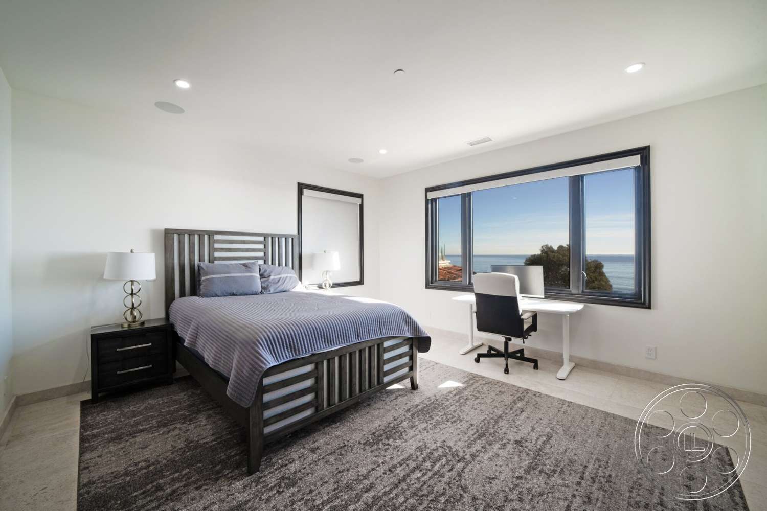 Medit 169 - striped bedding, contemporary desk, recessed ceiling lights, dark wood bed frame, light grey carpet flooring, marble floor tiles, modern bedside lamp, light-colored painted walls, black and white office chair, large rectangular window with ocean view