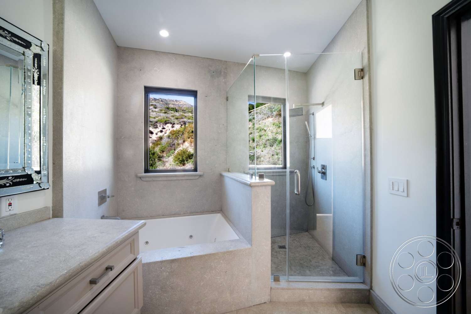 Medit 169 - neutral color palette, natural light, glass shower enclosure, smooth concrete walls, interior bathroom, marble countertop vanity, framed mirror with decorative detailing, rectangular window with mountain view, textured stone shower floor, bathtub with built-in step