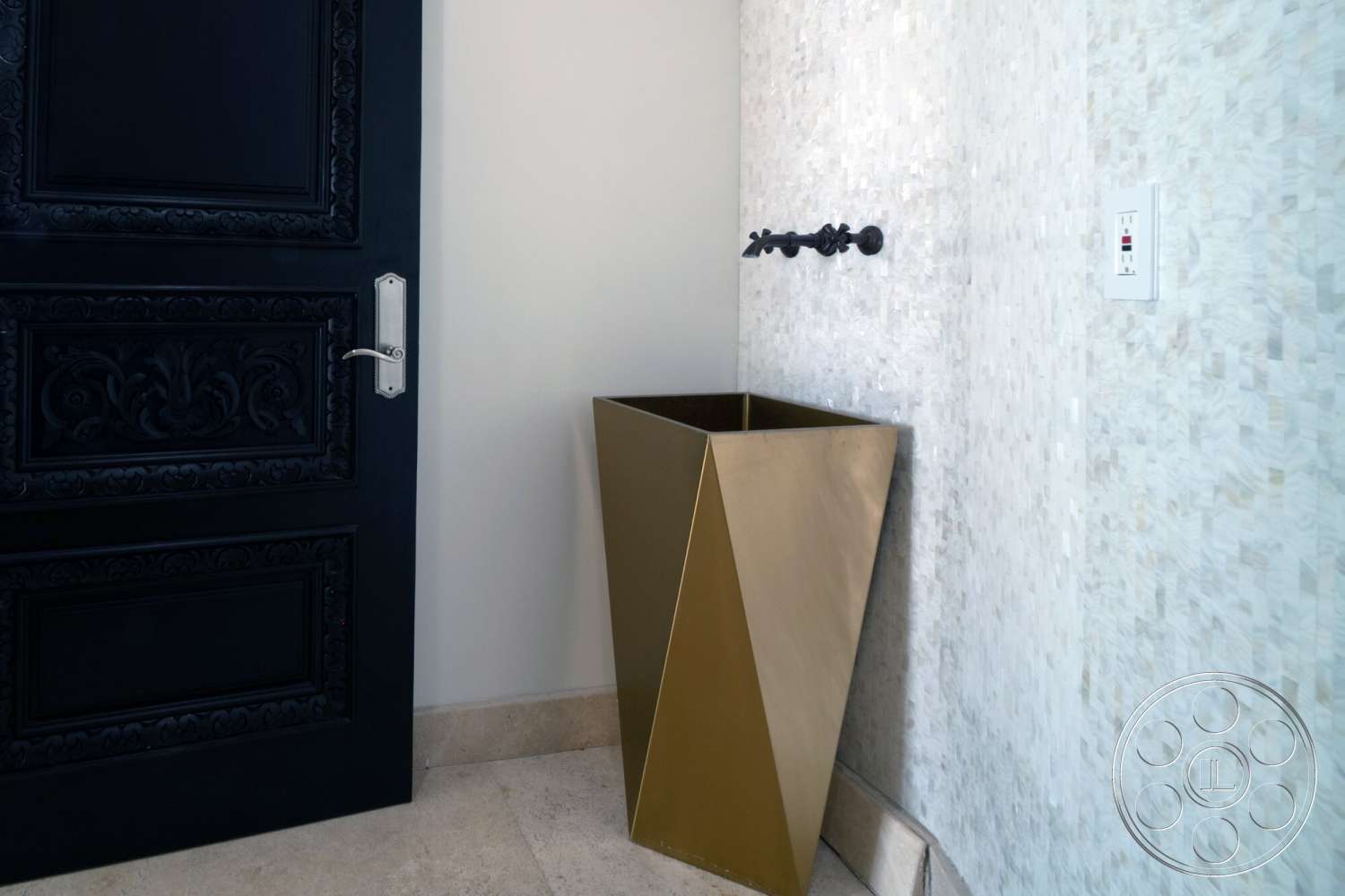Medit 169 - neutral color palette, natural stone flooring, ornate black wooden door, gold metallic planter, textured cream stone wall, decorative wall-mounted faucet, minimalist angular shapes