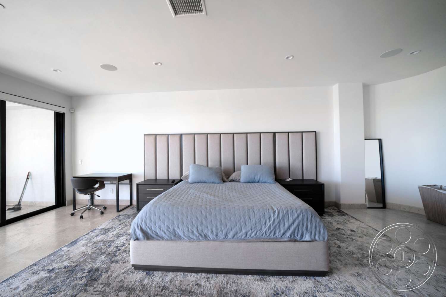 Medit 169 - minimalist decor, neutral color palette, black nightstands, soft area rug, textured plaster walls, curved wall design, accent pillows, queen-size upholstered bed, tile bedroom flooring, modern desk with rolling chair, floor-to-ceiling glass sliding door, panoramic view window