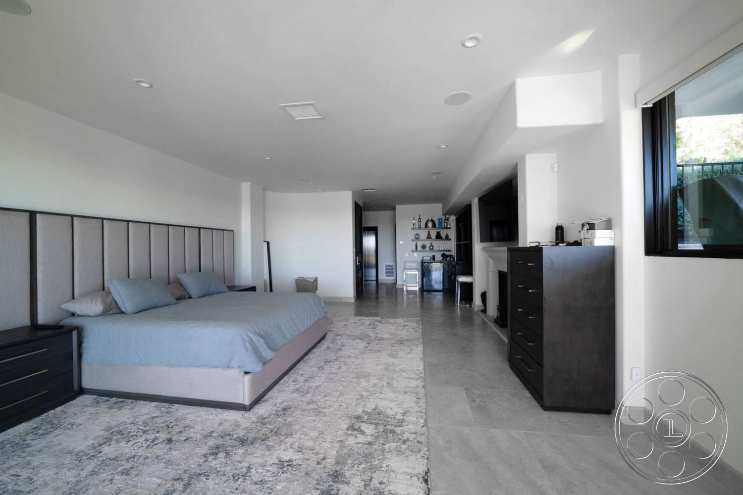 Medit 169 - modern decor, open layout, floor-to-ceiling windows, minimalistic design, light gray walls, dark wood dresser, recessed ceiling lights, concrete tile flooring, large bedroom, upholstered bed with gray headboard, luxury carpet flooring
