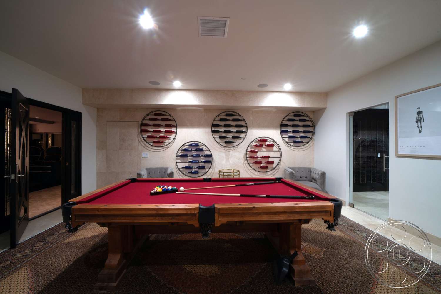 Medit 169 - recessed lighting, decorative area rug, sliding glass door, textured ceiling, white painted walls, exposed stone feature wall, pool table with red felt surface, dark wooden pool table frame, round wall-mounted wine racks, chic gray armchairs, black framed door, cream-colored floor tiles