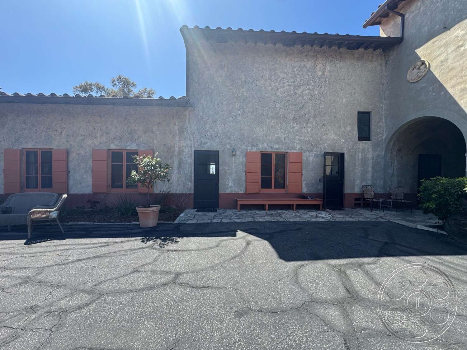 Farmstead Garden - exterior, landscaped garden, paved driveway, black door, planter with greenery, terracotta roof, stucco walls, modern outdoor seating, stone patio flooring, orange wooden window shutters
