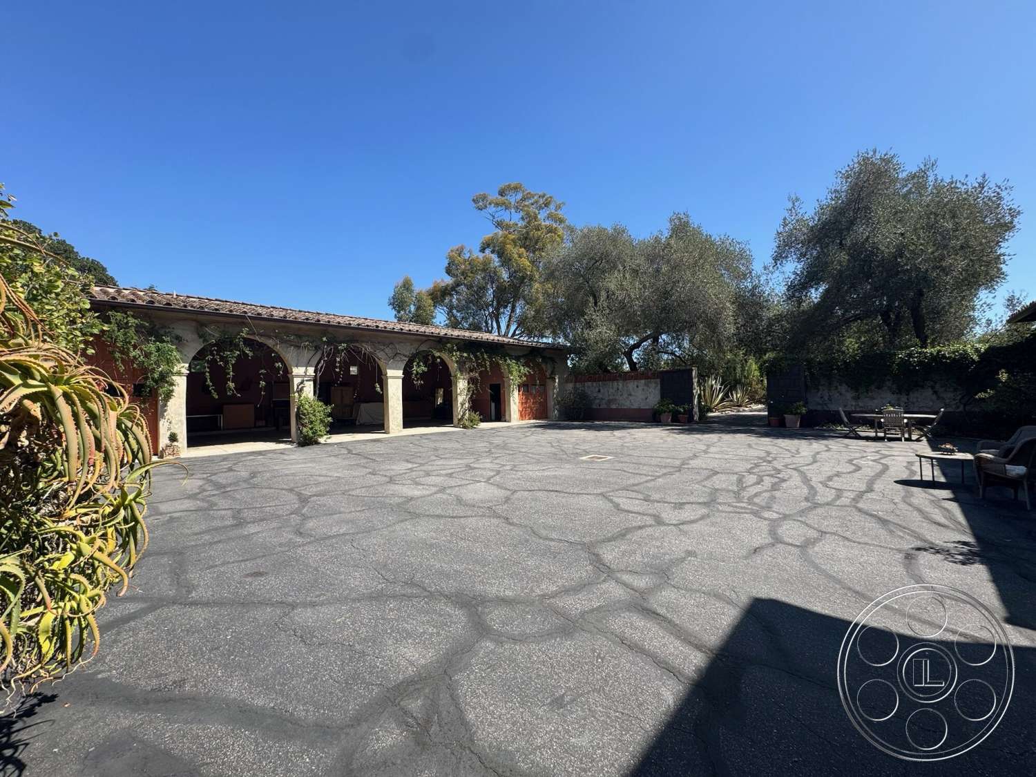 Farmstead Garden - exterior, scenic view, outdoor seating area, asphalt driveway, arched entryway, sunny outdoor setting, landscaped garden area, residential courtyard, terra cotta tile roof, stone column supports, oleander plants, patio lounging space