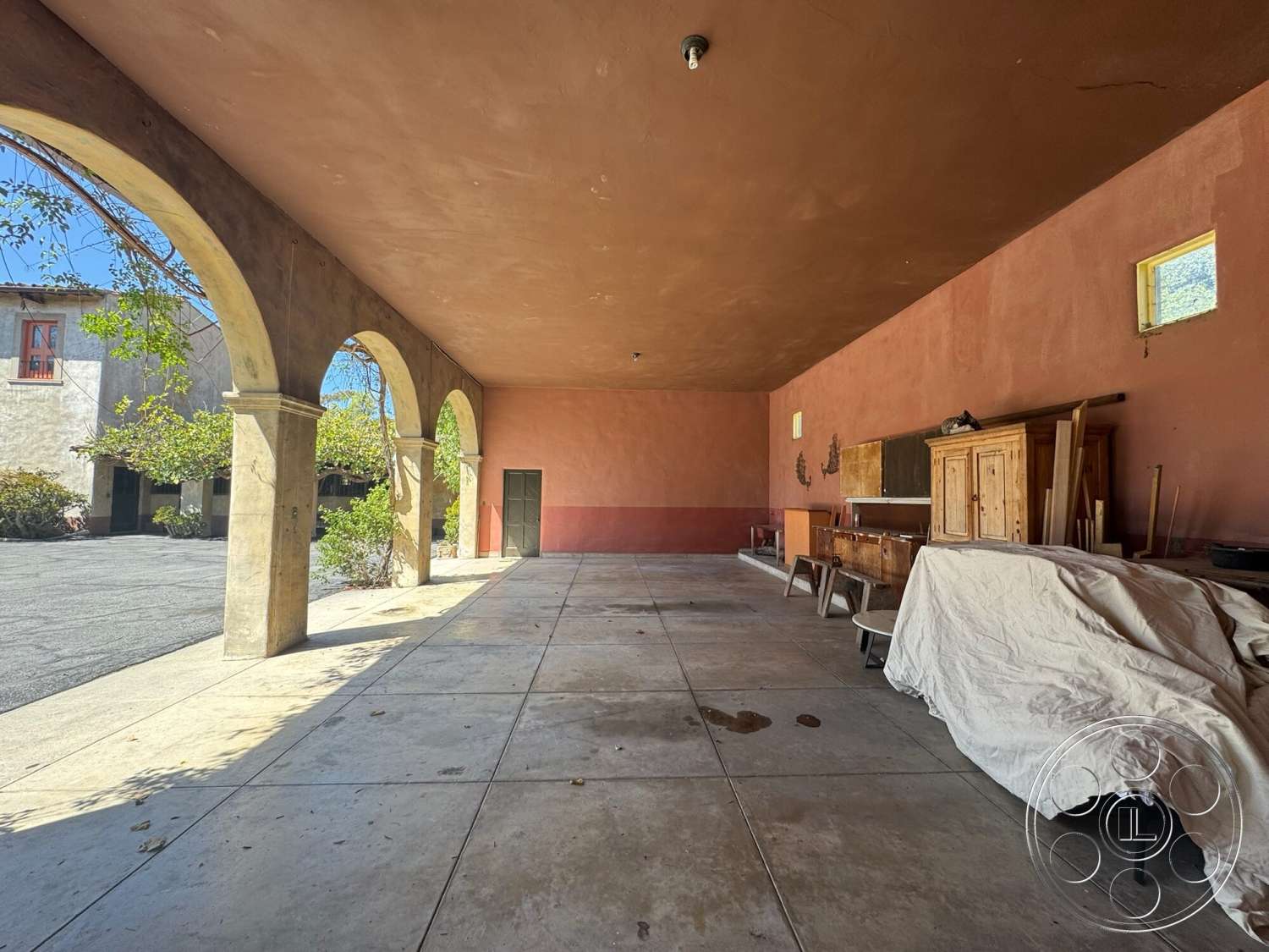 Farmstead Garden - natural light, exterior, wooden furniture, stucco walls, minimal landscaping, arched openings, concrete patio flooring, rustic architectural style, courtyard setting, painted plaster ceiling