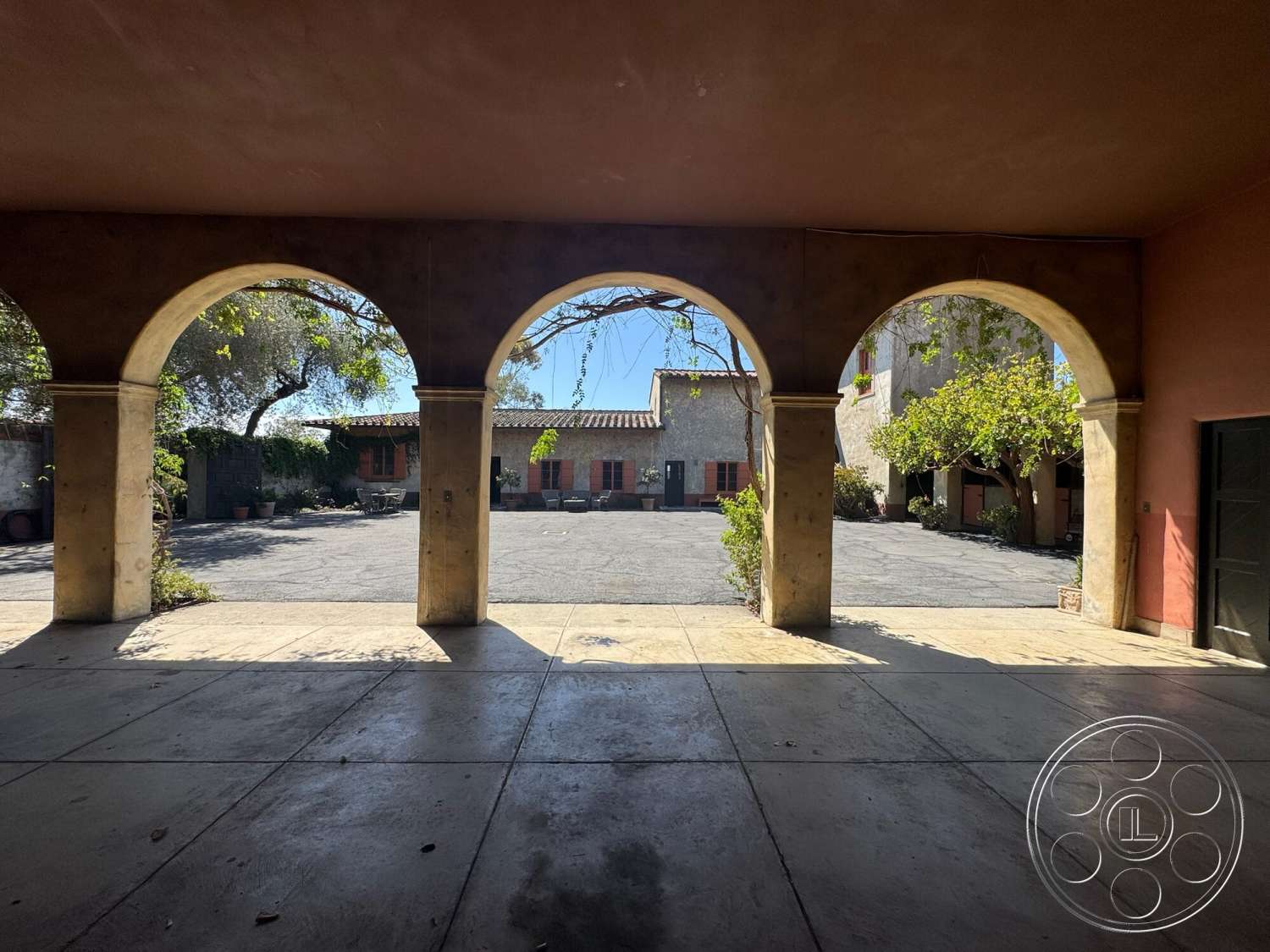 Farmstead Garden - exterior, textured plaster walls, Mediterranean architectural style, red window frames, concrete terrace flooring, arcs of stone arches, courtyard with potted plants, cobblestone courtyard, vines climbing up structures