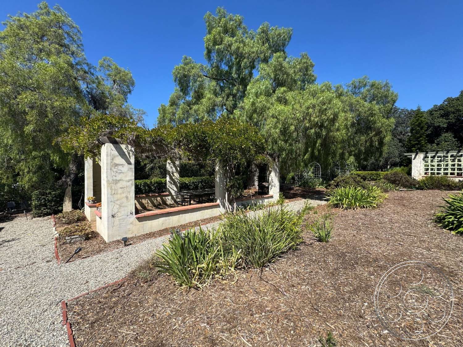 Farmstead Garden - exterior, gravel pathway, open-air seating area, landscaped garden area, wood pergola structure, native plant landscaping, stone garden edging, concrete patio walls, mulch garden bed
