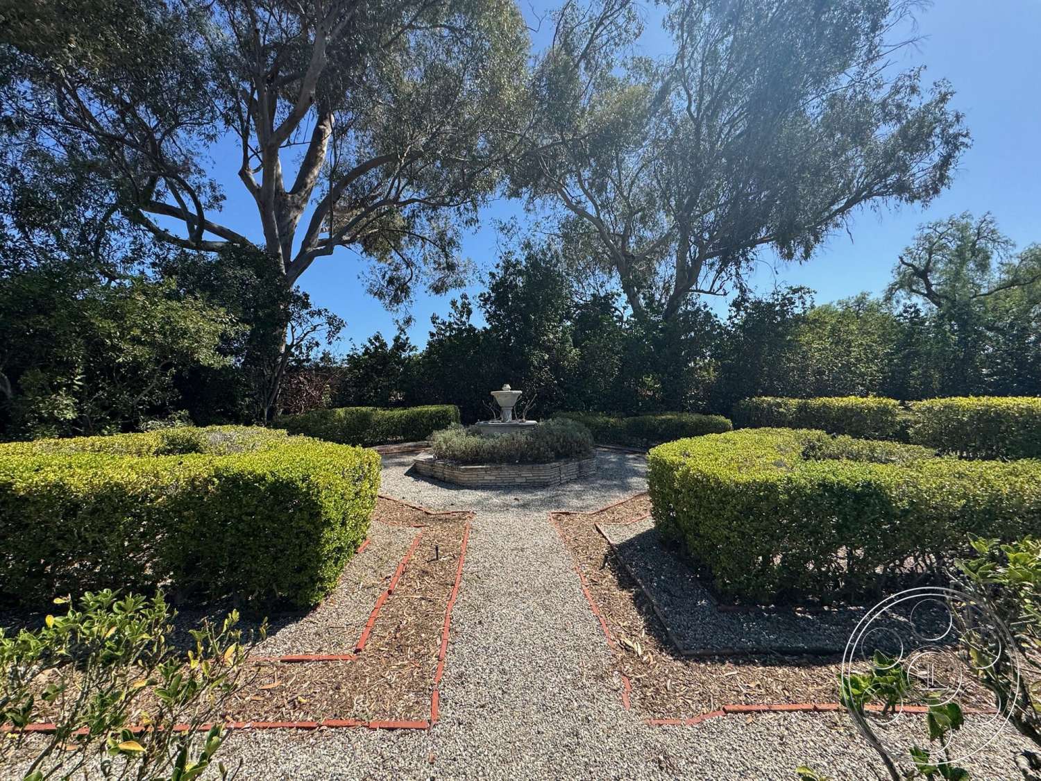 Farmstead Garden - gravel pathway, planted trees, green hedges, formal garden layout, hedge landscaping, circular fountain, sunny outdoor environment, exterior garden setting, small concrete edging