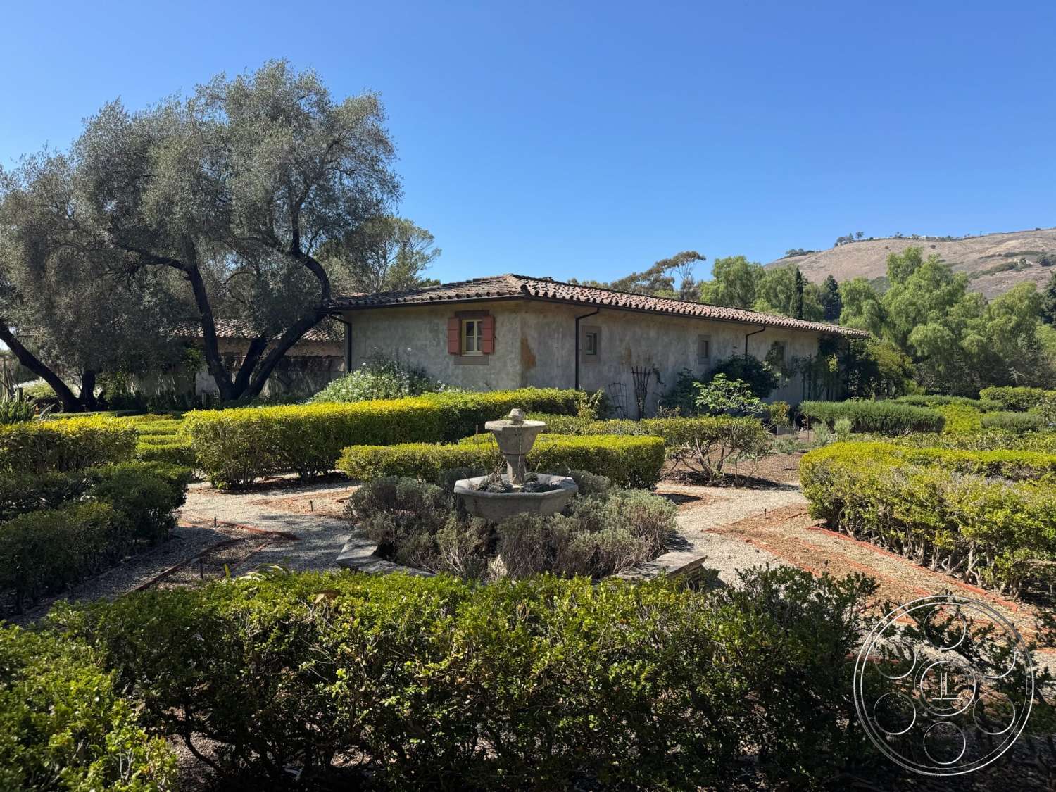 Farmstead Garden - exterior, landscaped garden, gravel pathways, stucco walls, terra cotta roof, Mediterranean architectural style, ornamental fountain, mountain view setting, slate roof tiles, archtop window frames, hedged shrubbery