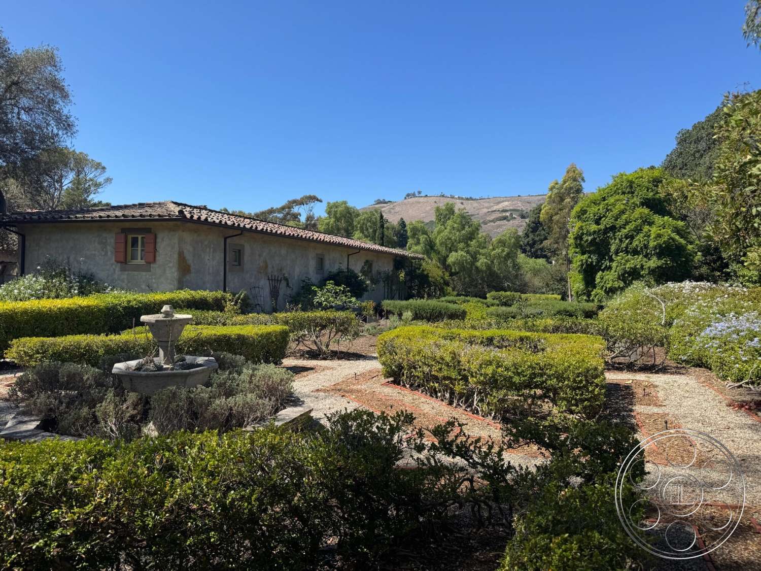 Farmstead Garden - exterior, landscaped garden, gravel pathway, terracotta roof tiles, stucco walls, fountain feature, hillside location, native shrubbery, wood window shutters, rectangular garden beds